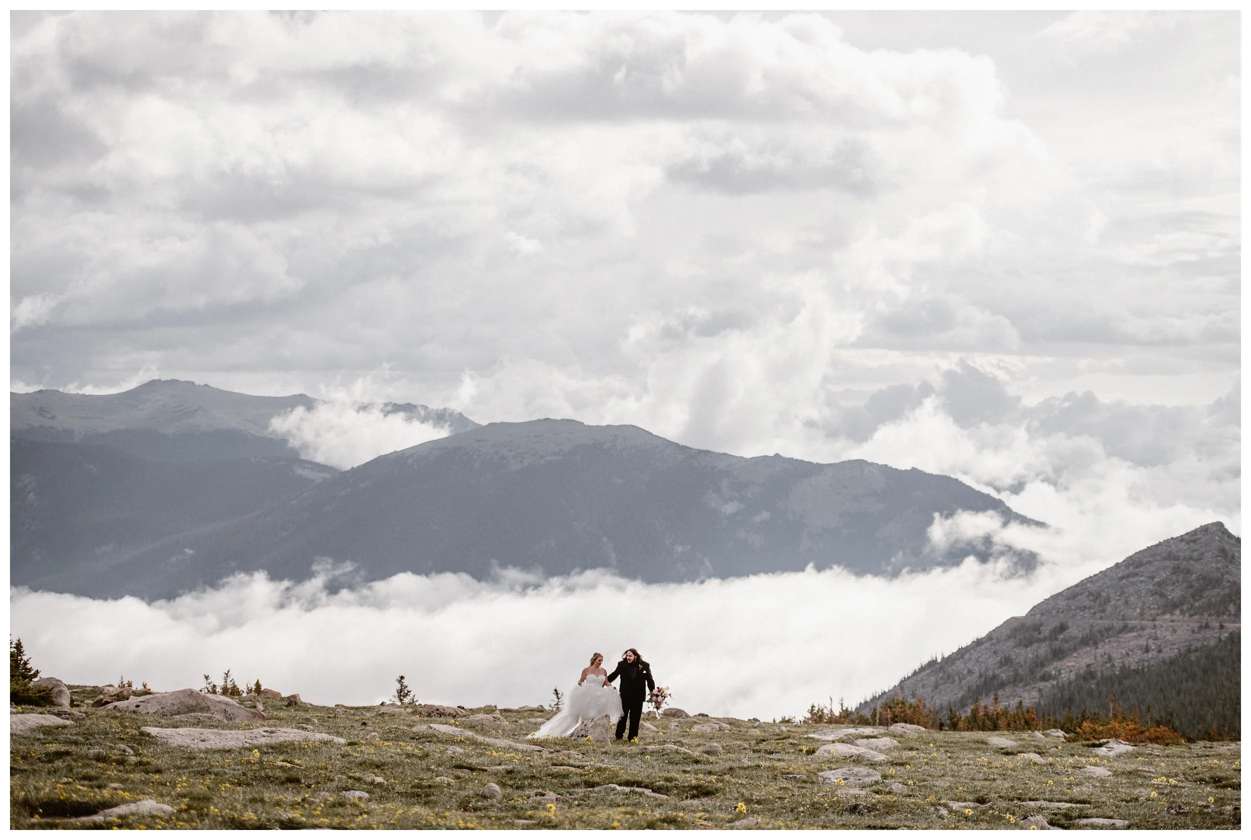 The clouds roll through the valley while Alicia and Zach walk through Trail Ridge Road during their first look before their elopement ceremony in Rocky Mountain National Park. Photo by Adventure Instead, Maddie Mae.