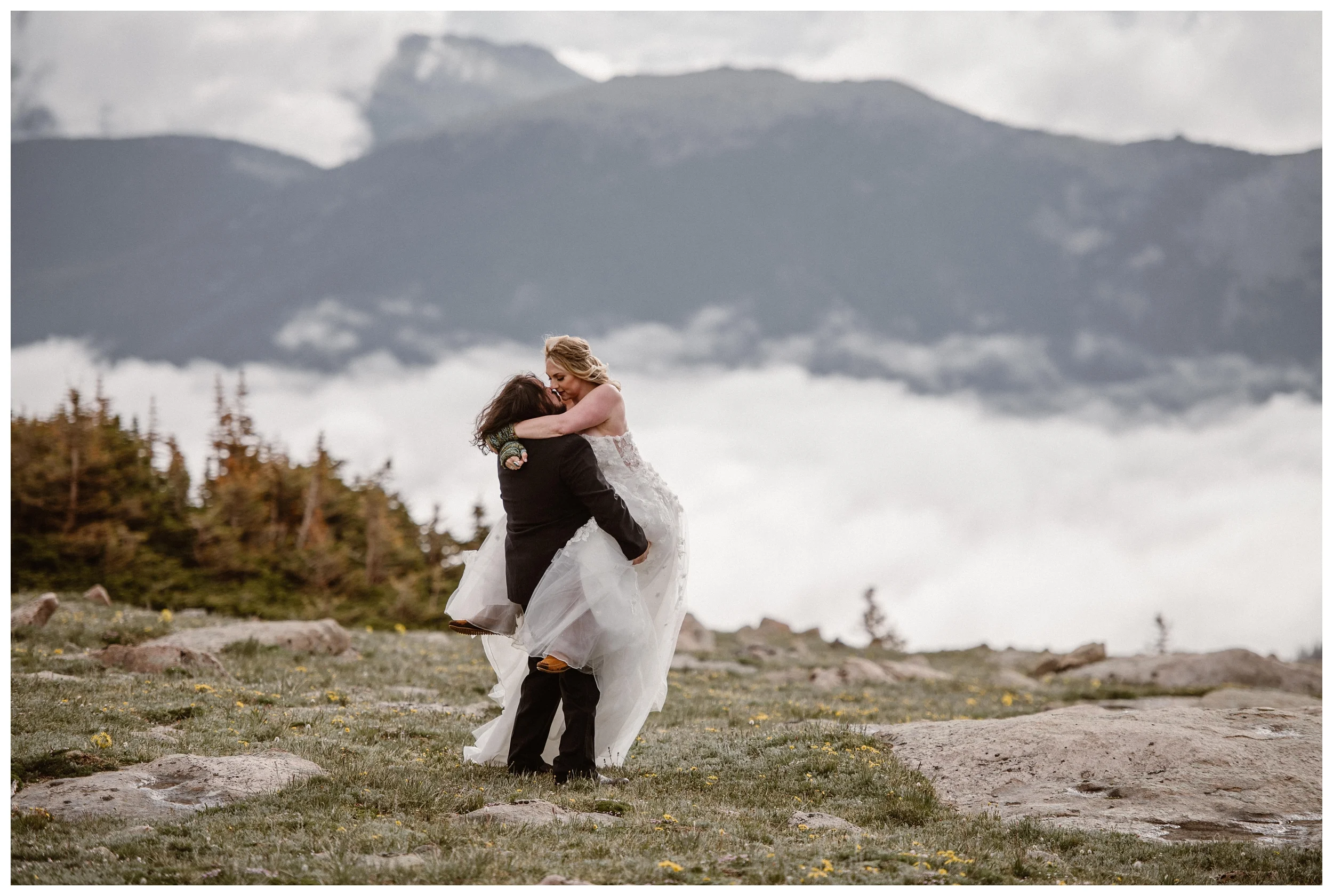 Alicia and Zach embrace at the top of Trail Ridge Road in Rocky Mountain National Park with an impressive display of cloud inversion behind them. Photo by Adventure Instead, Maddie Mae.