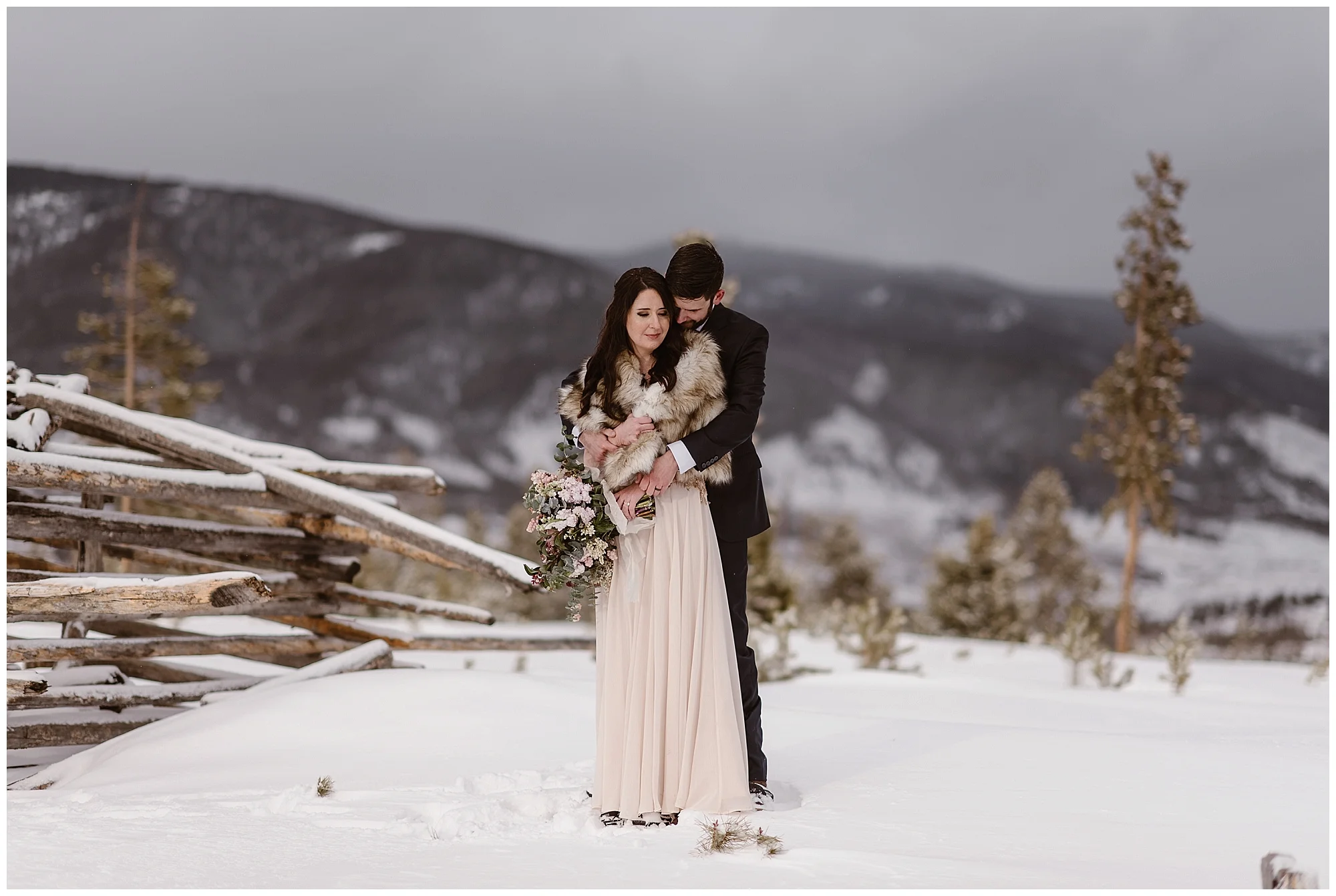 The snow capped Rockies behind them, Marlayna and Austin embrace following their winter elopement ceremony at Sapphire Point in Dillon, Colorado. Photo by Adventure Instead, Maddie Mae Elopement Photographers.