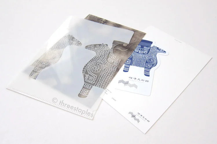 Small, white folder and postcards + museum ticket