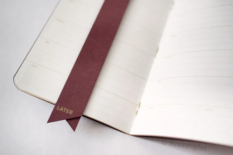 A nice bonus for subscribers: a matching bookmark with gold text. It's a long, thin strip of paper folded in half, labeled “NOW” on one side and “LATER” on the other.