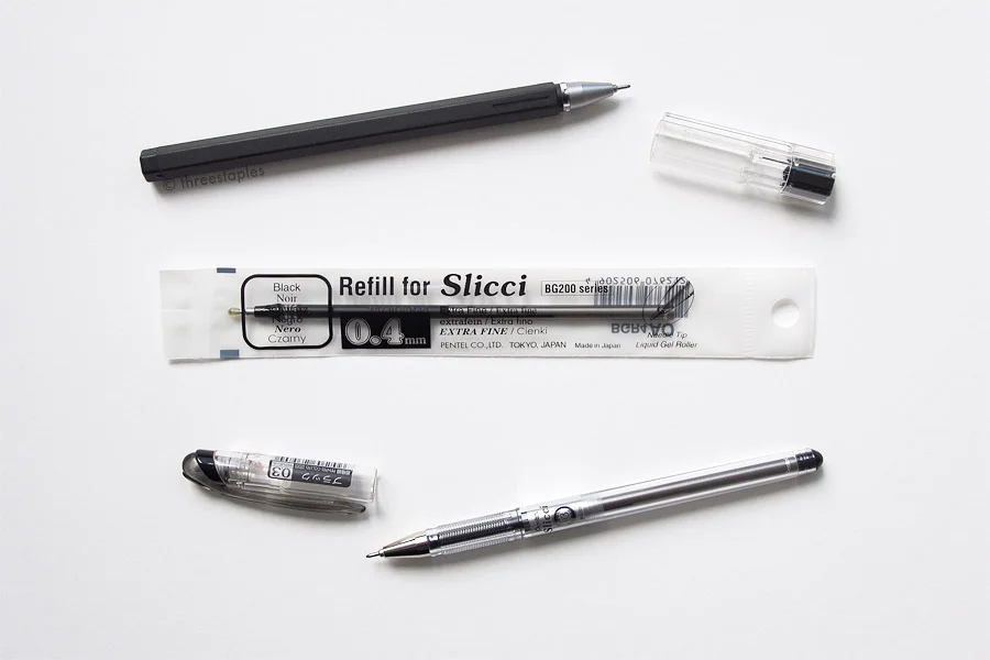 Uncapped: Muji (top) and Pentel Slicci in black (bottom), with Slicci refill 0.4mm still in its packaging in the middle.