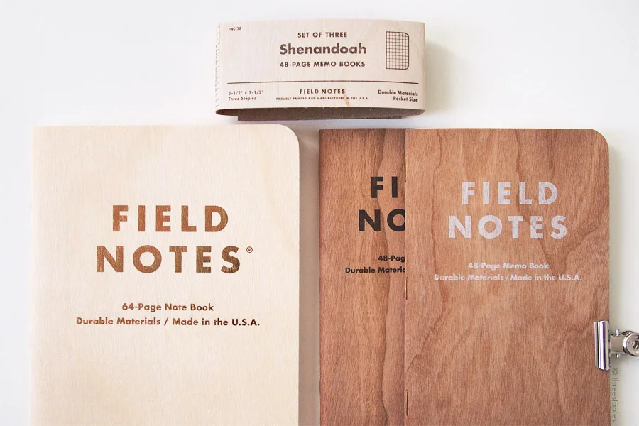 Field Notes with wood: Starbucks Roastery Edition (with birch) on the left, Cherry Graph and Shelterwood on the right, both with cherry wood. The Shenandoah belly band on the top also features birch veneer.