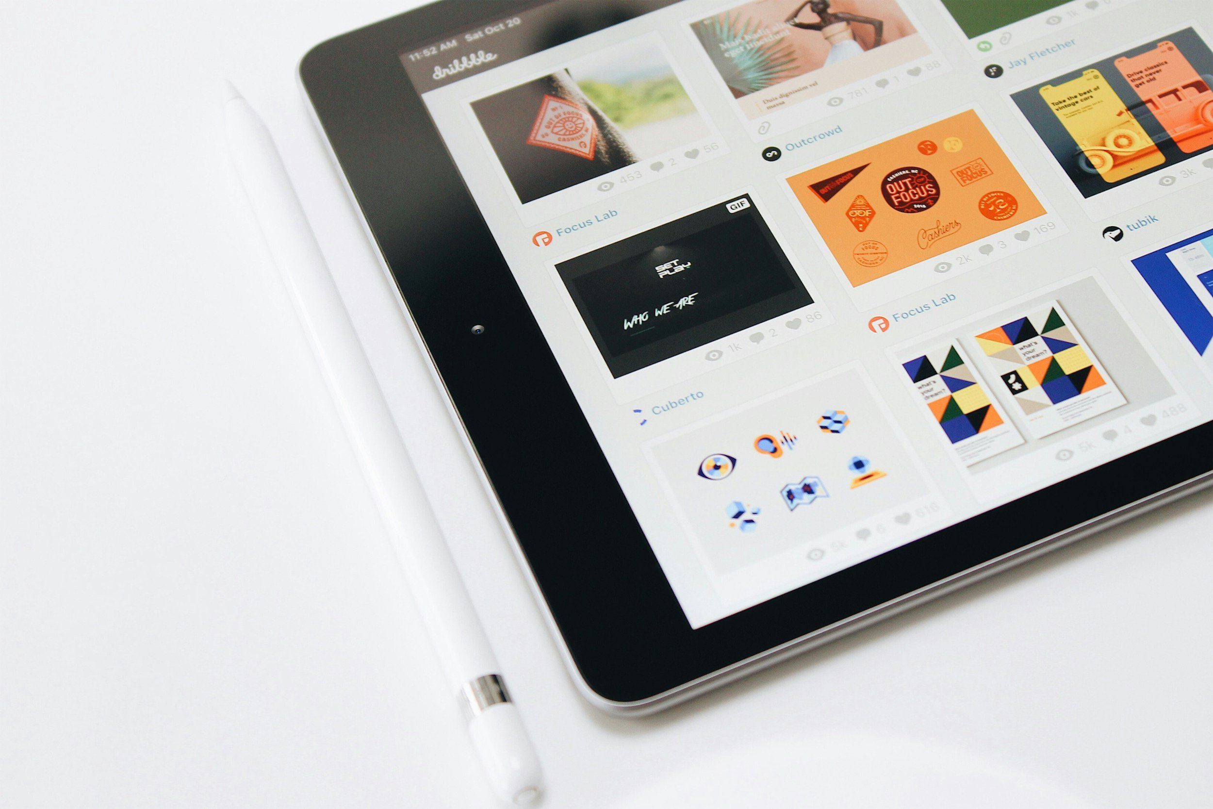 A tablet displaying a social media platform with various images, posts, and icons, placed on a white surface.