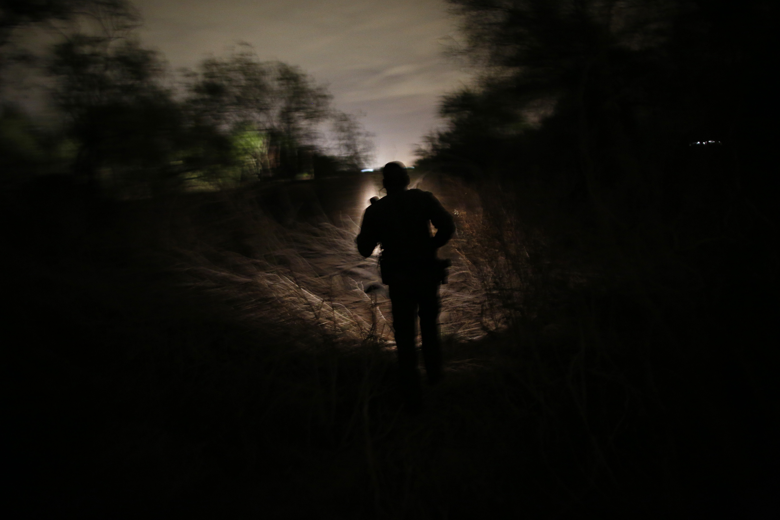   A U.S. Border Patrol agent looks for a group of people who crossed the border into the U.S. from Mexico in Mission, TX. 2013  