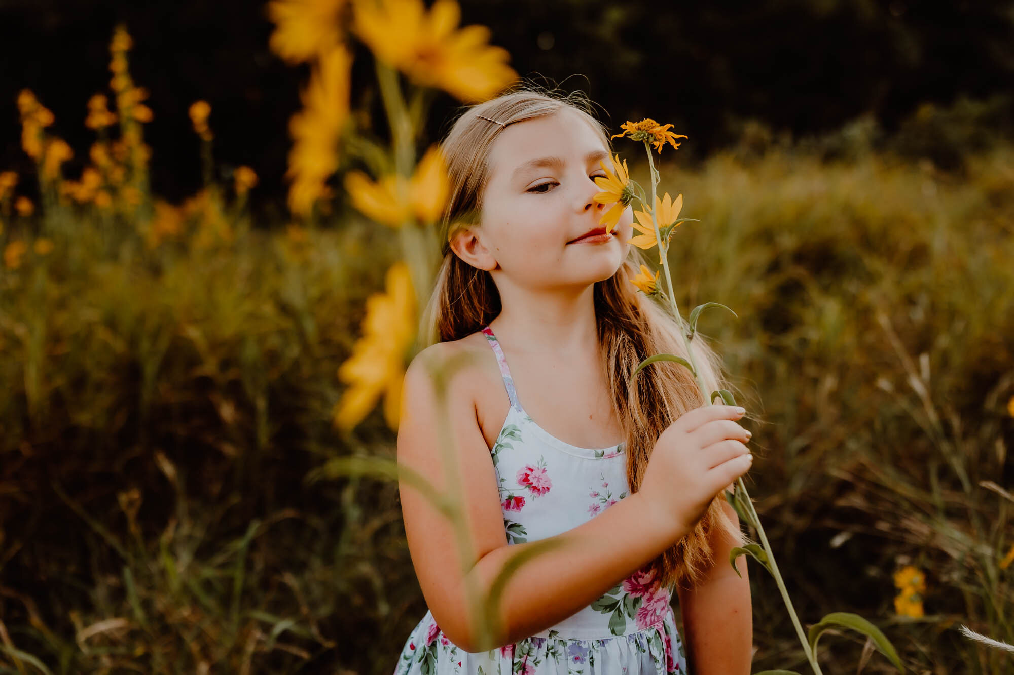girl sniffing sunflower for photos