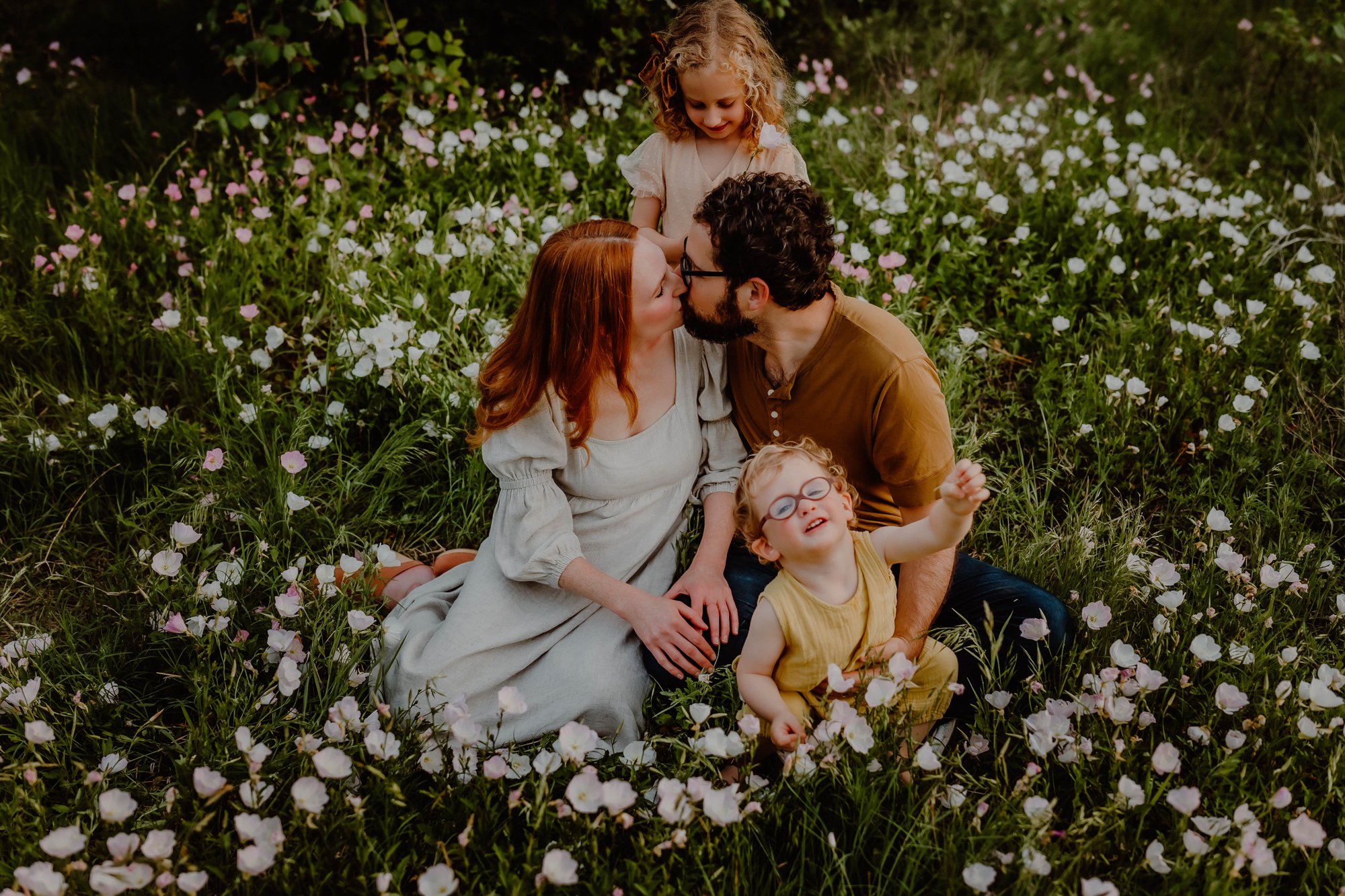 family sits in field of wildflowers