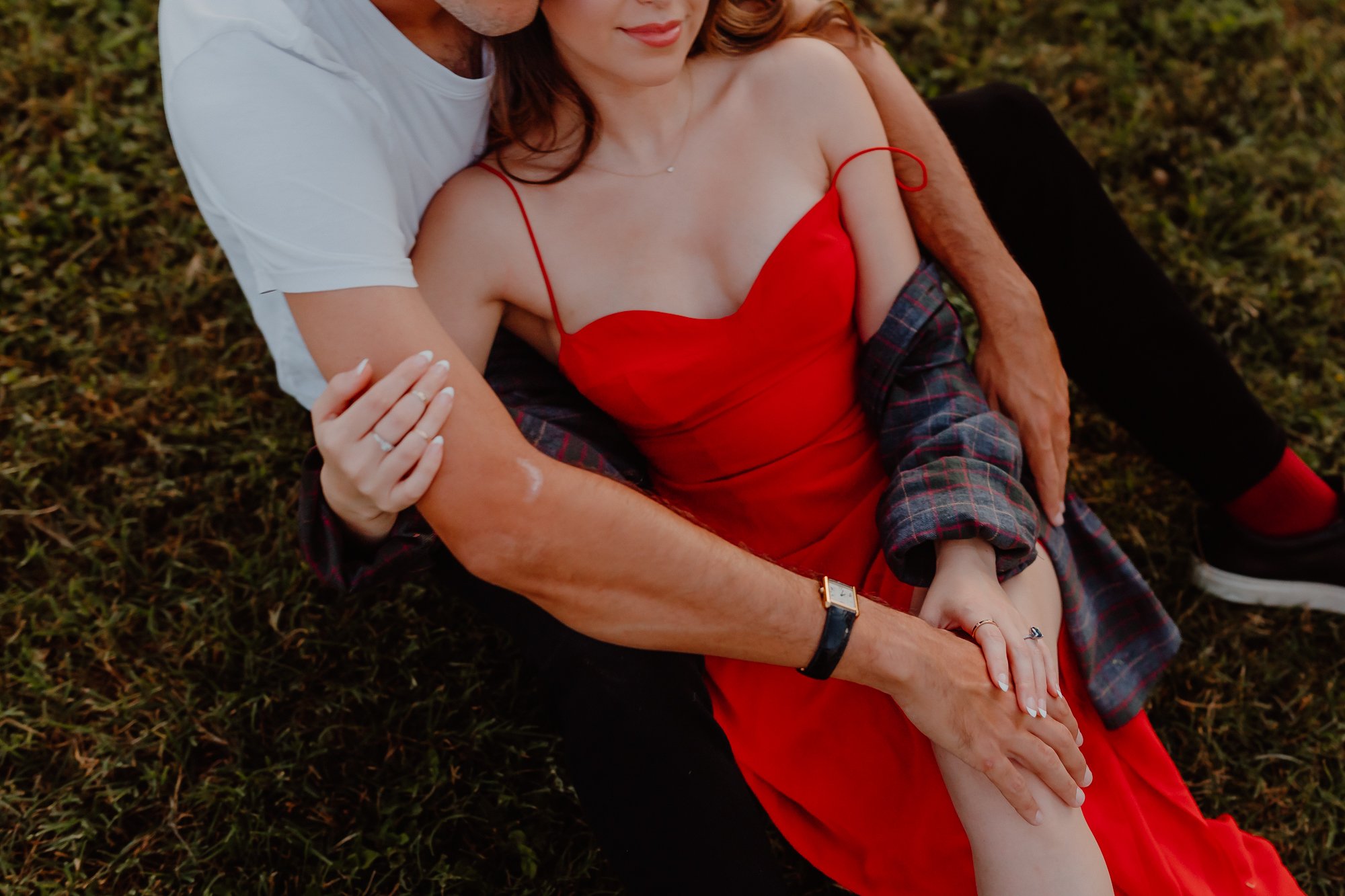 girl in red dress laying in fiancé's lap