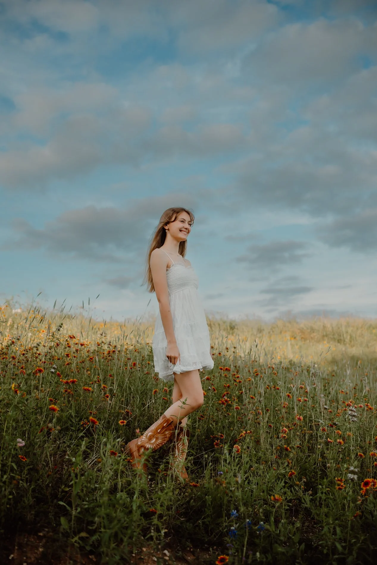 Outdoor senior portrait of Dylann surrounded by pink and yellow Texas wildflowers in the Hill Country outside Austin.
