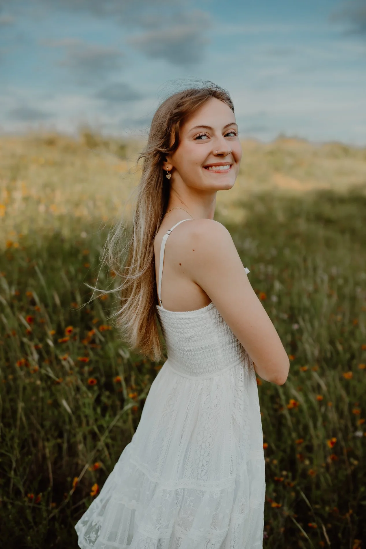 Lifestyle senior portrait photographer in Austin, TX photographs Dylann walking through a spring wildflower field at golden hour.