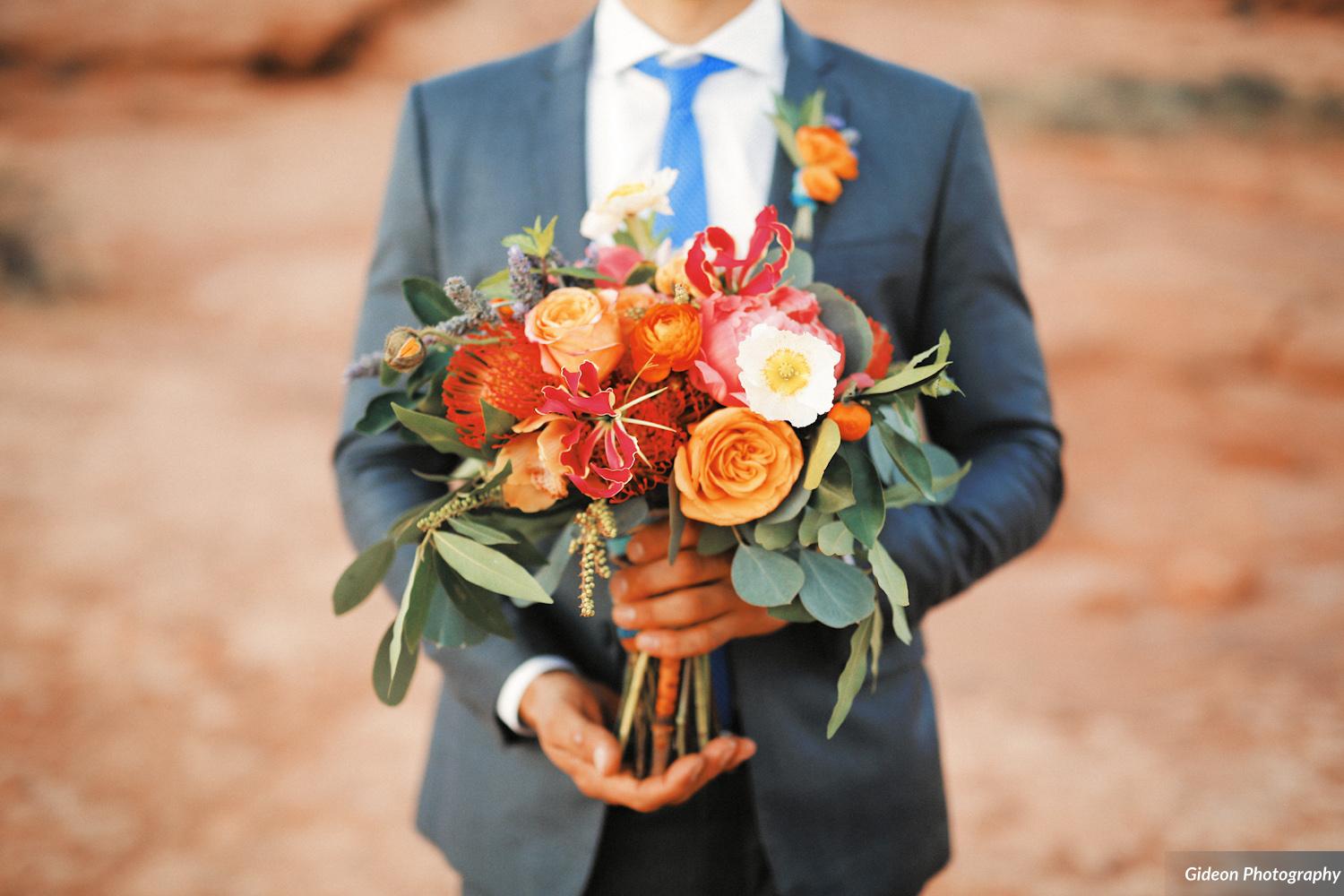 bridal bouquet with gold roses, coral peonies, anemones, gloriosa lilies, and protea