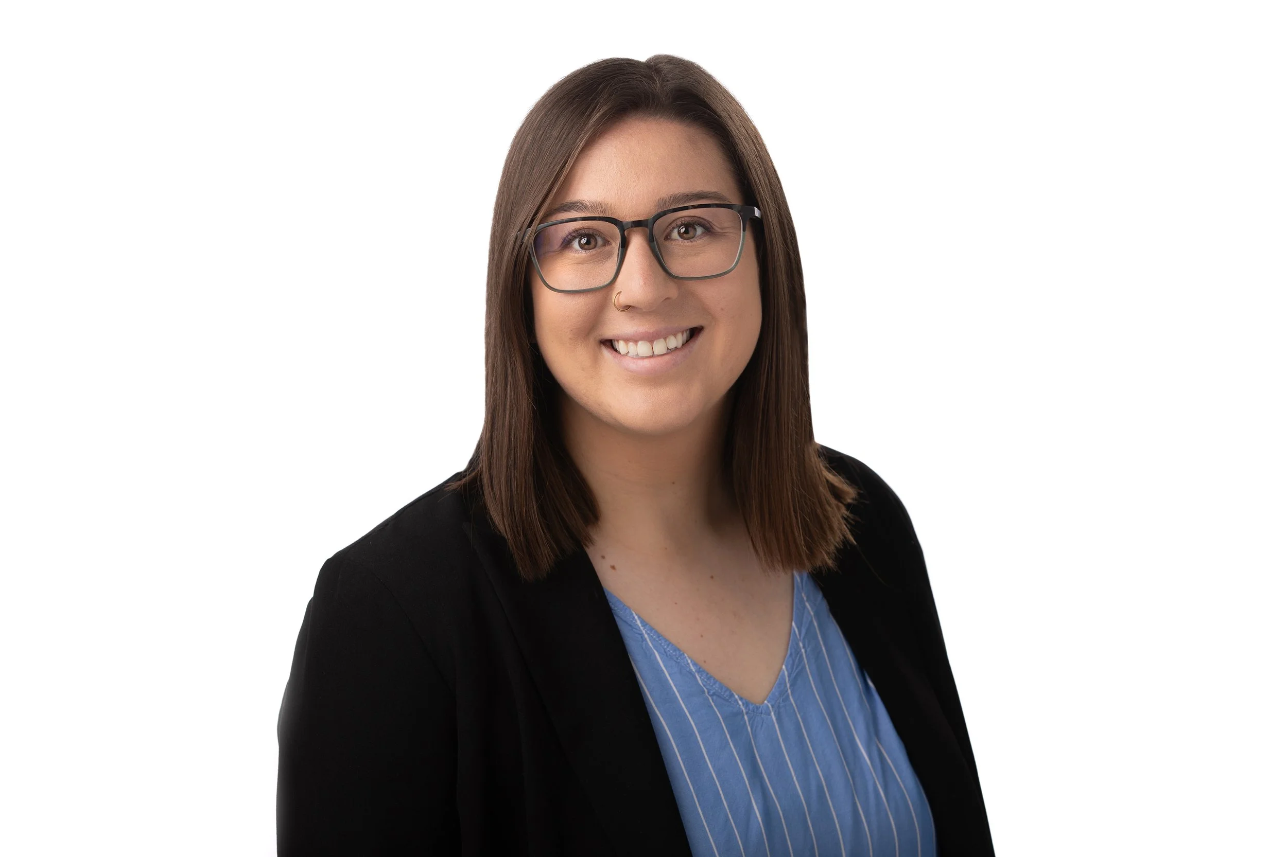 A woman with shoulder-length brown hair, glasses, and a nose ring, smiling, dressed in a black blazer and a blue striped blouse.