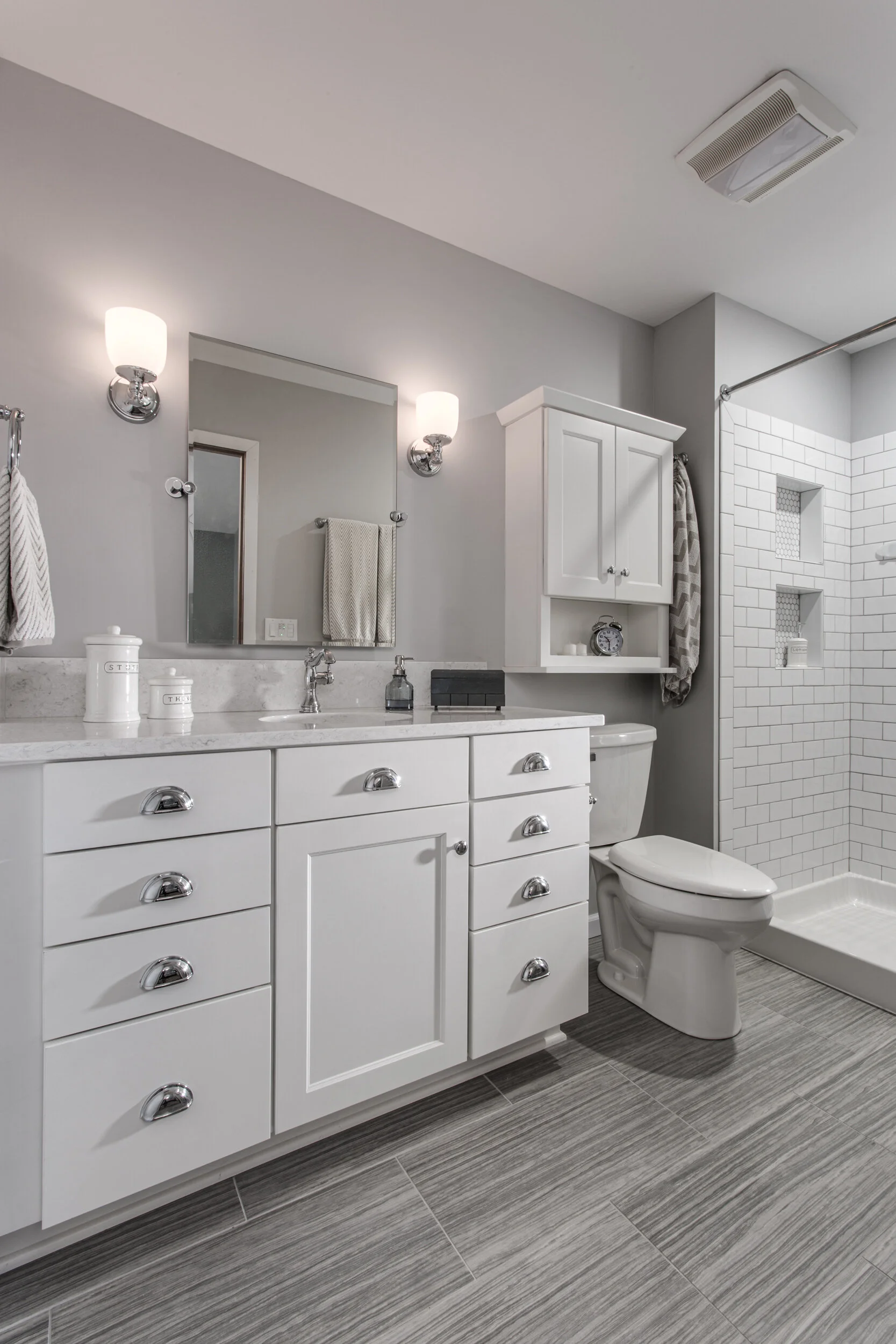 Modern bathroom with white vanity, gray tile floor, glass-enclosed shower, and gray walls.