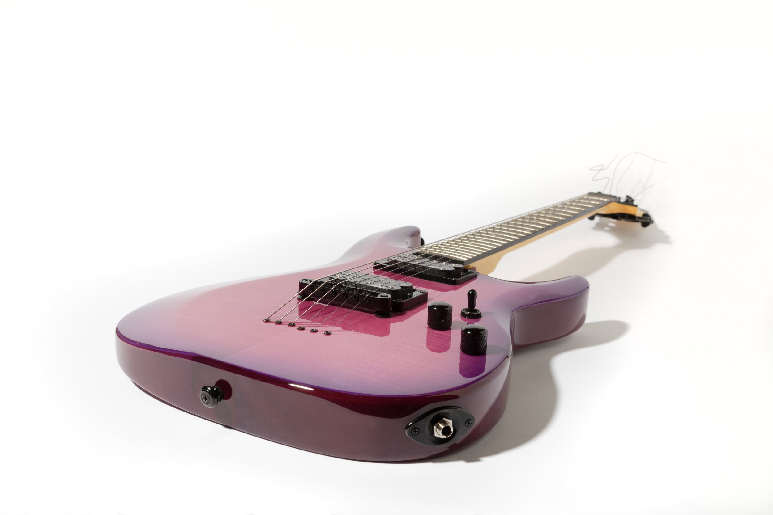 A pink electric guitar lying on a white background. Photo by studio product photographer Tom Krueger, Milwaukee, Wisconsin.