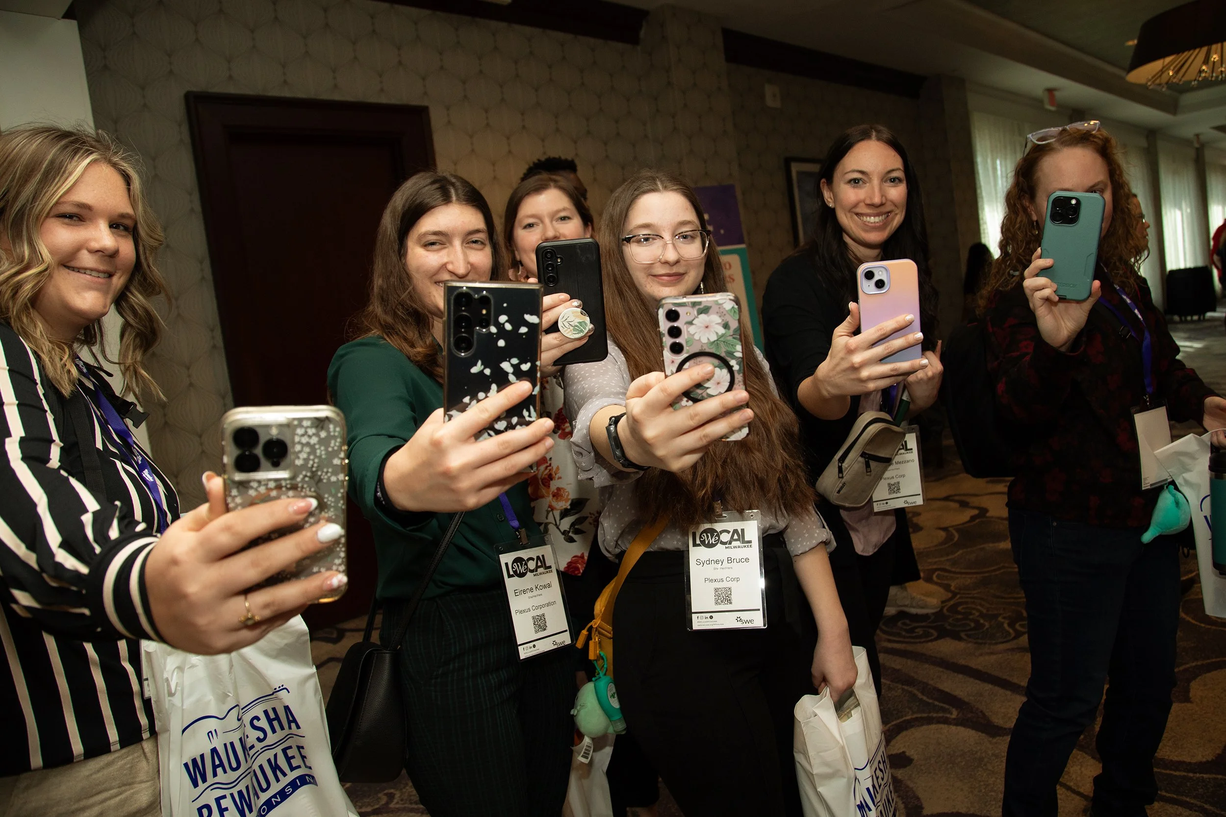 Corporate event photography by Tom Krueger, photographer, Milwaukee, Wisconsin. Group of women taking a photo with their smartphones in an indoor setting.