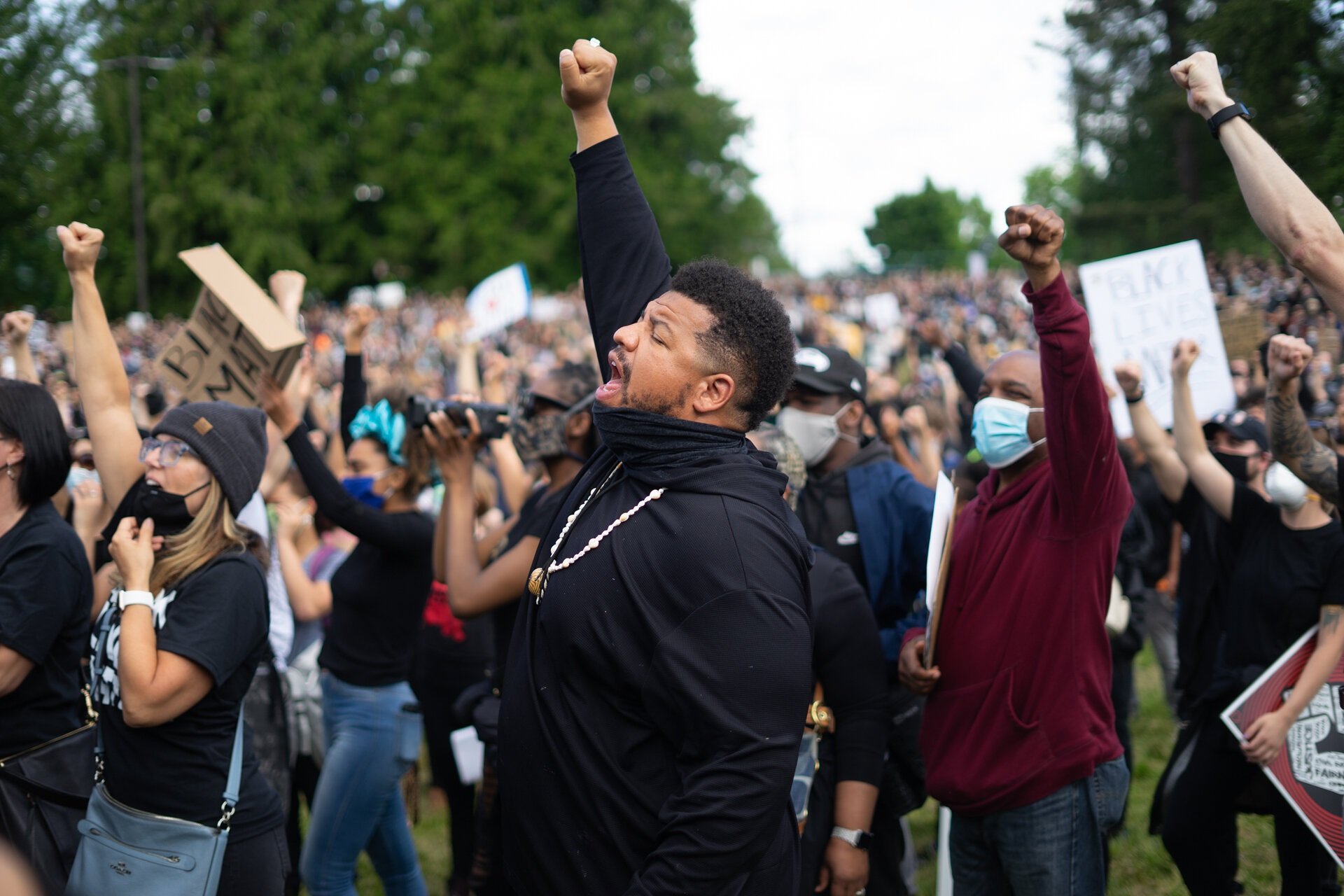  Jordan Chaney raises his fist during a moment of silence for lives lost to gun and police violence. Thousands gather to march from Othello Park in Seattle’s South end.  