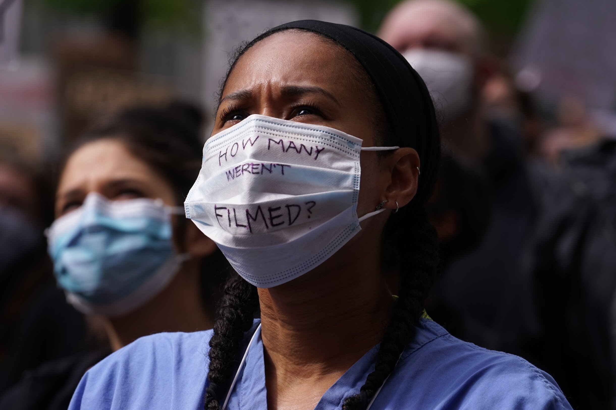   A healthcare worker looks on as speakers address a large crowd outside Seattle’s city hall. Thousands of medical professionals, students and civilians gather in solidarity with the Black Lives Matter movement. 