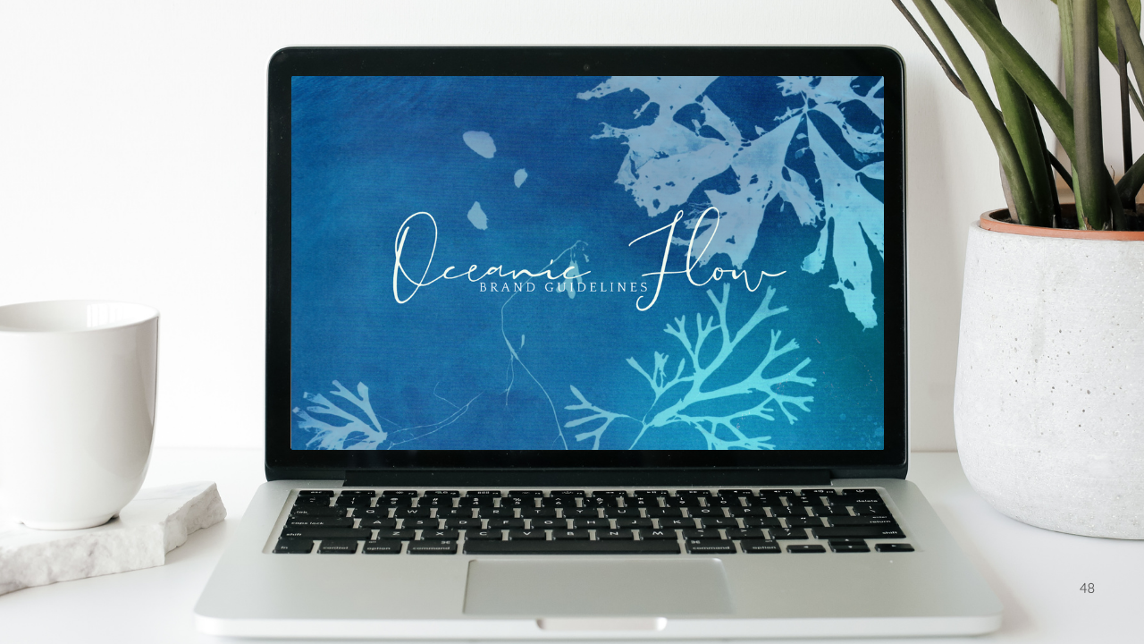 laptop on a white table with a white mug and green plant in a white pot. Oceanic Flow blue sea image on the screen of the laptop.