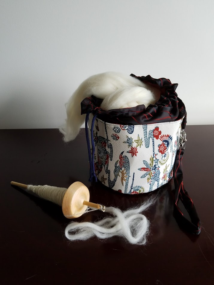 This round project bag closes with a draw string top and has a detachable wristlet. It's perfect for a large knitting project or a giant ball of roving. 7" x 10" x 10"