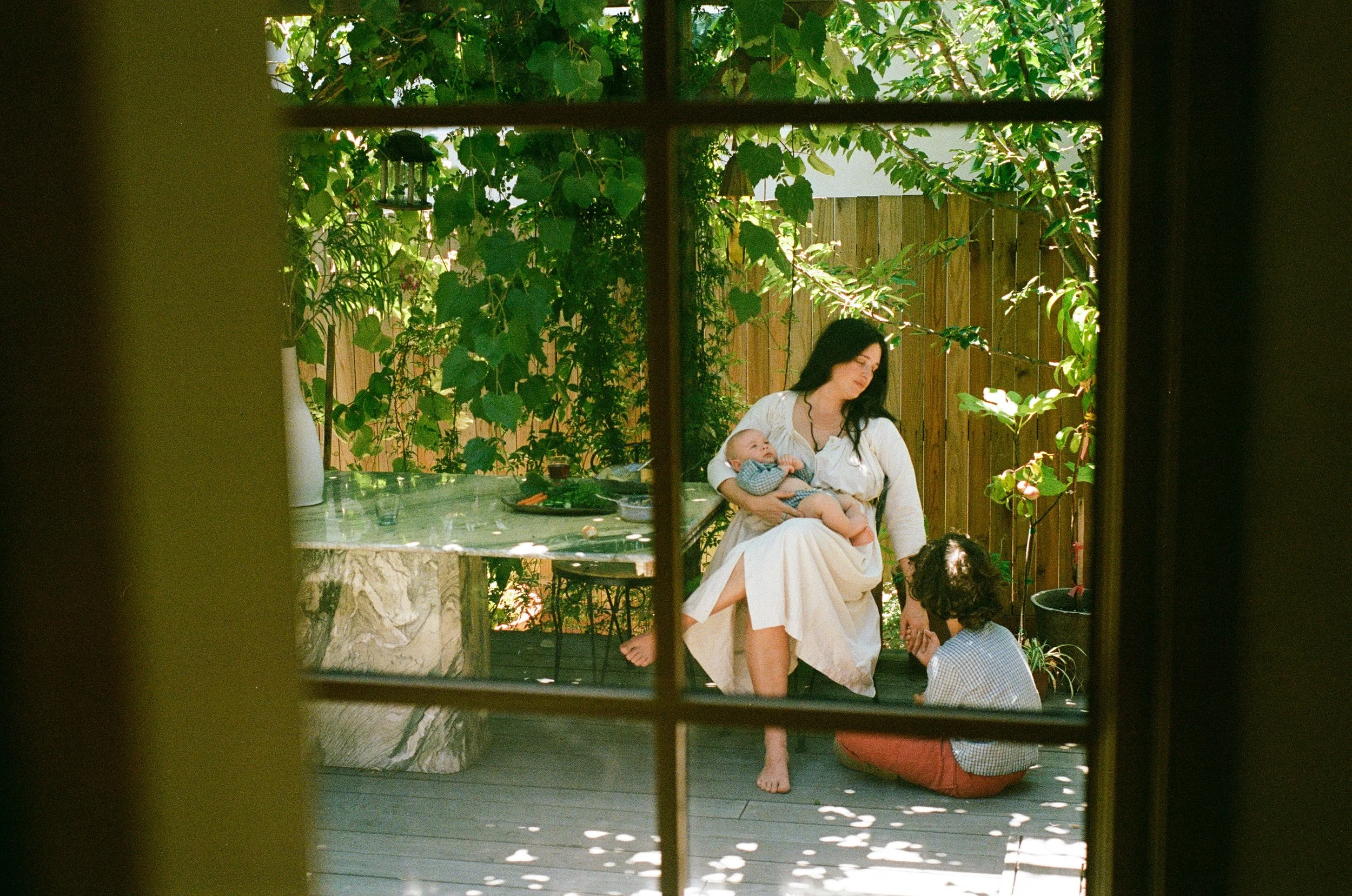 Sacramento family photography of a mother with her baby and young child in a backyard garden