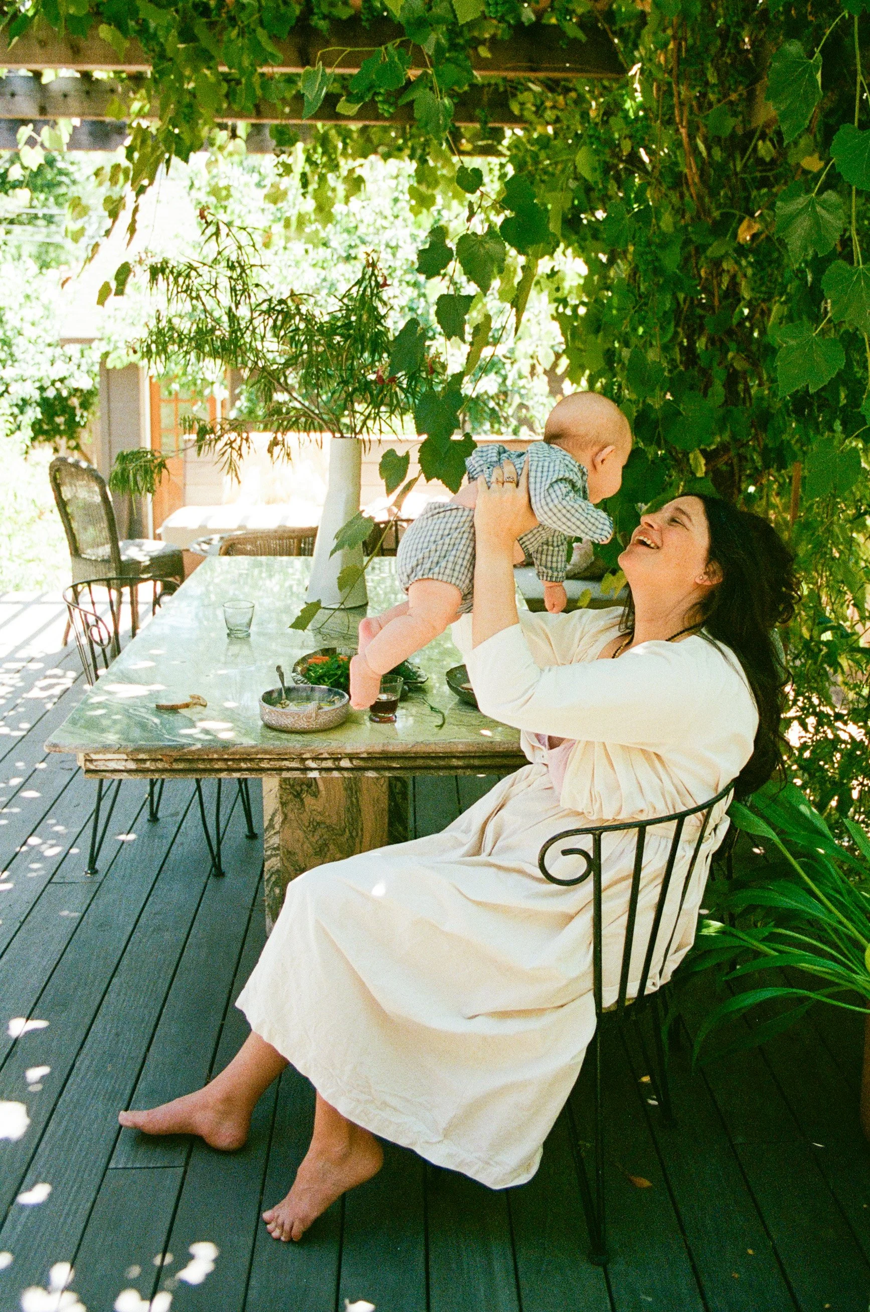 Sacramento family photographer captures a mother joyfully lifting her baby during a candid backyard family photography session