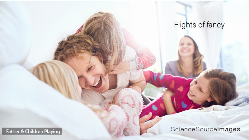 PLAYFUL FATHER AND DAUGHTERS TICKLING ON BED