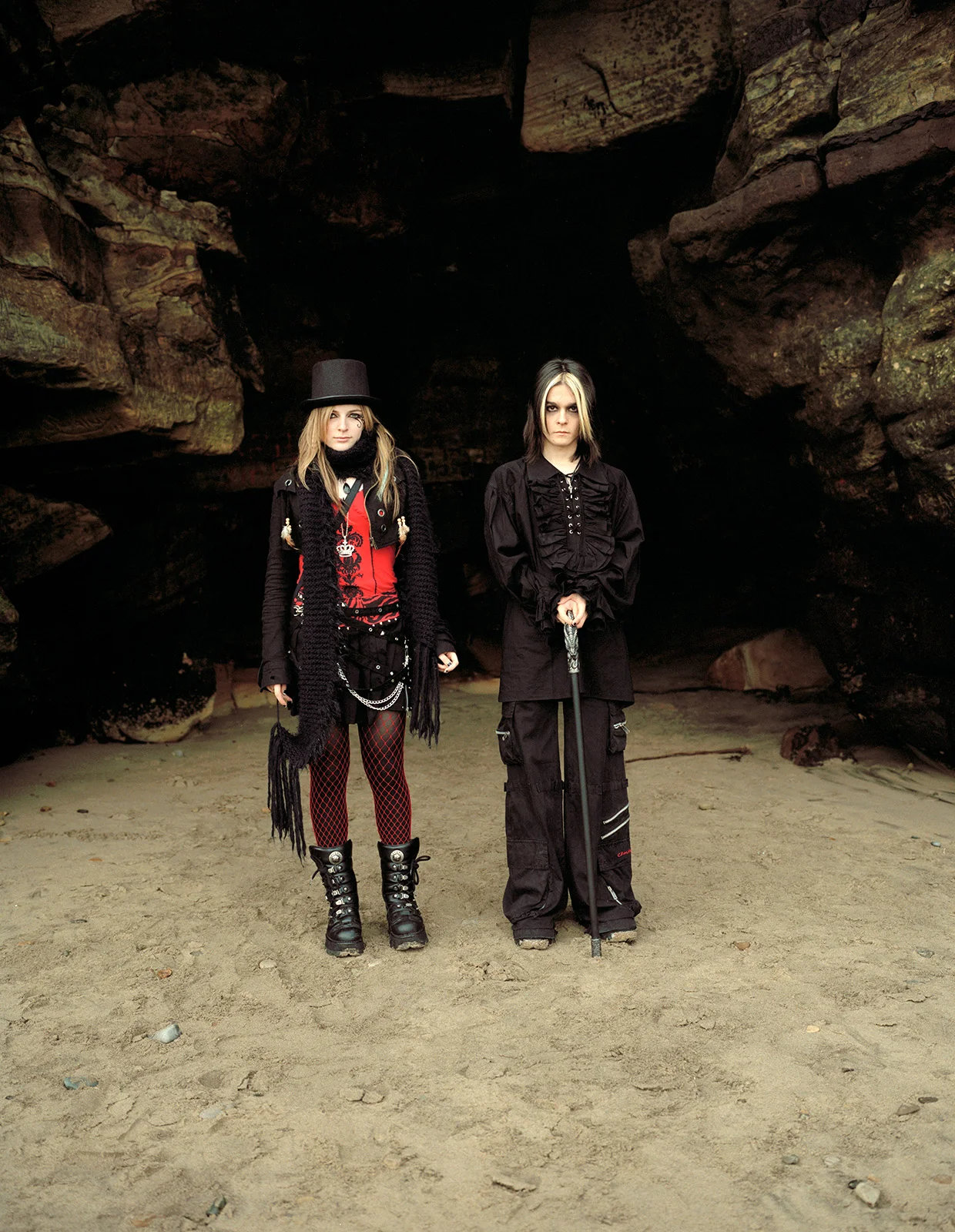 goth couple gothic costume by cave on Whitby sands at Whitby Goth weekend