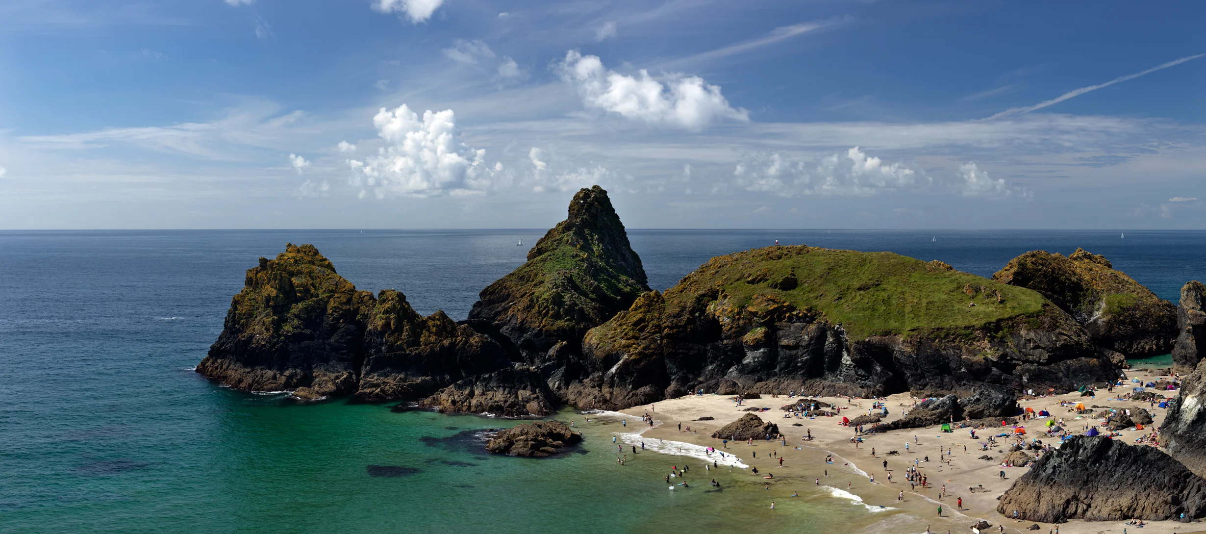 Headland and tidal islands with crowded beach Kynance Cove Cornwall