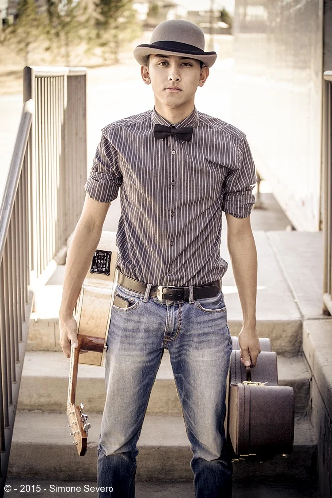 We call him T.J. He told me he wanted an outdoors portrait with his guitar. I met him in a mid afternoon, and I knew what I wanted. I asked him to sit in the stairs and play the guitar. Bonus: he picked the hat, the striped shirt and an old guitar c…