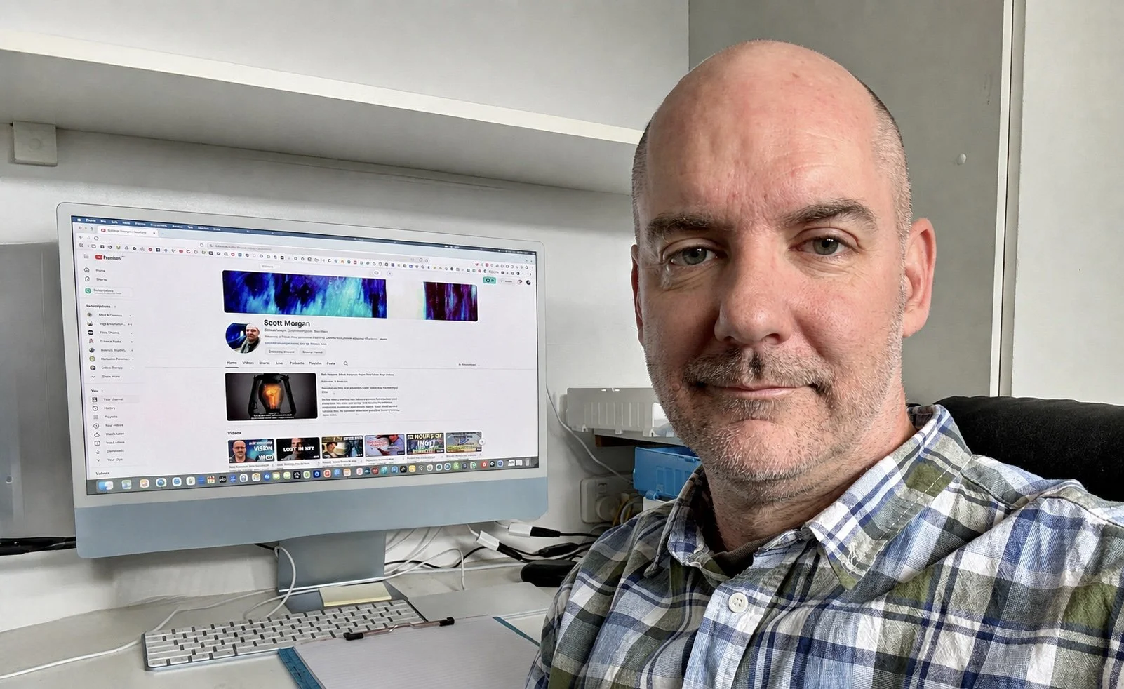 Scott Morgan seated at his desk beside a computer displaying his YouTube channel.