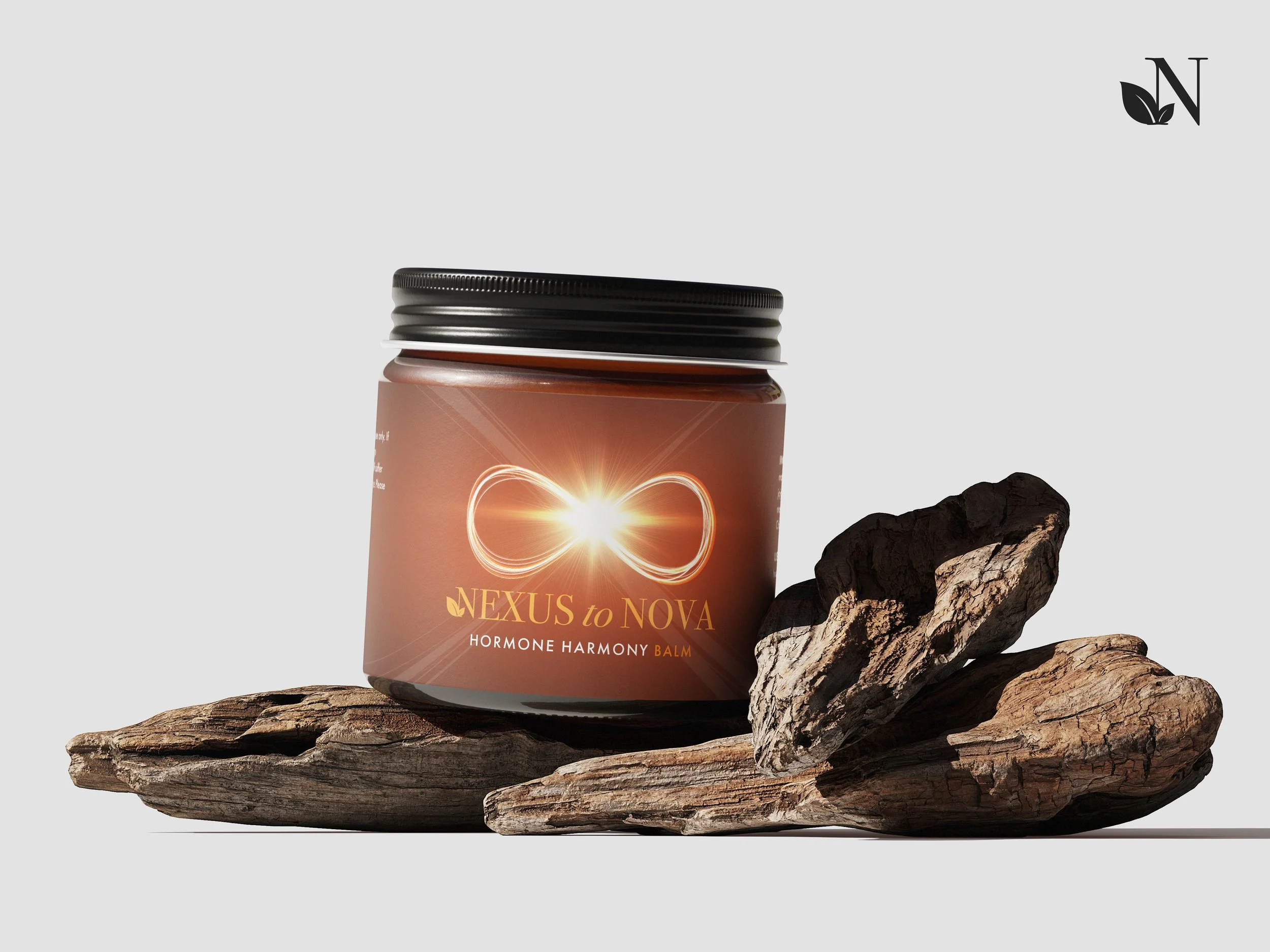 A brown container labeled 'NEXUS to NOVA Hormone Harmony Balm' with a glowing infinity symbol on it, placed on a piece of wood beside a small black rock.