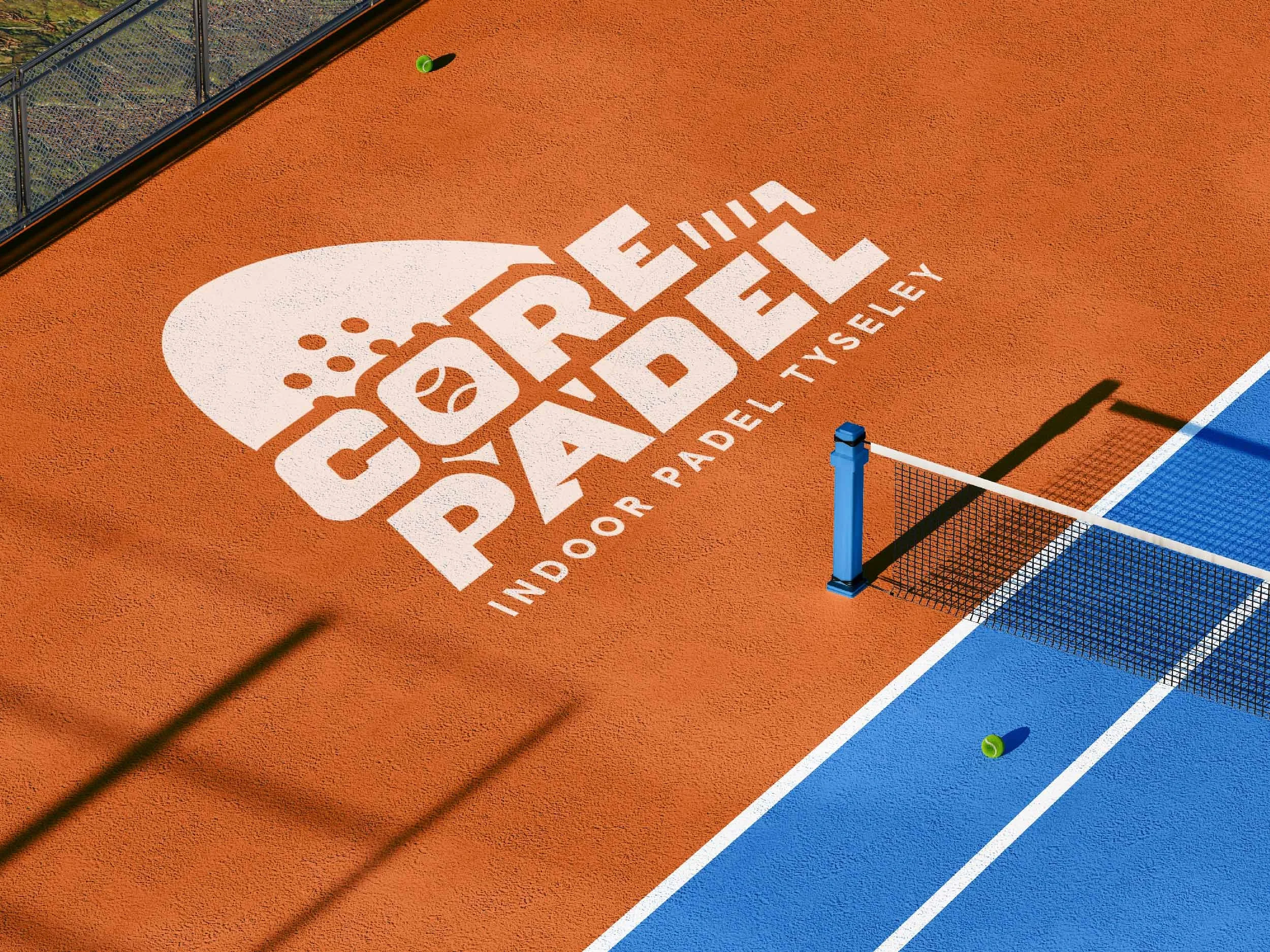 A tennis court with a large white logo and text that says Invited for real del Y SLEY. Part of the court is painted blue and orange, with a net and green tennis ball visible.