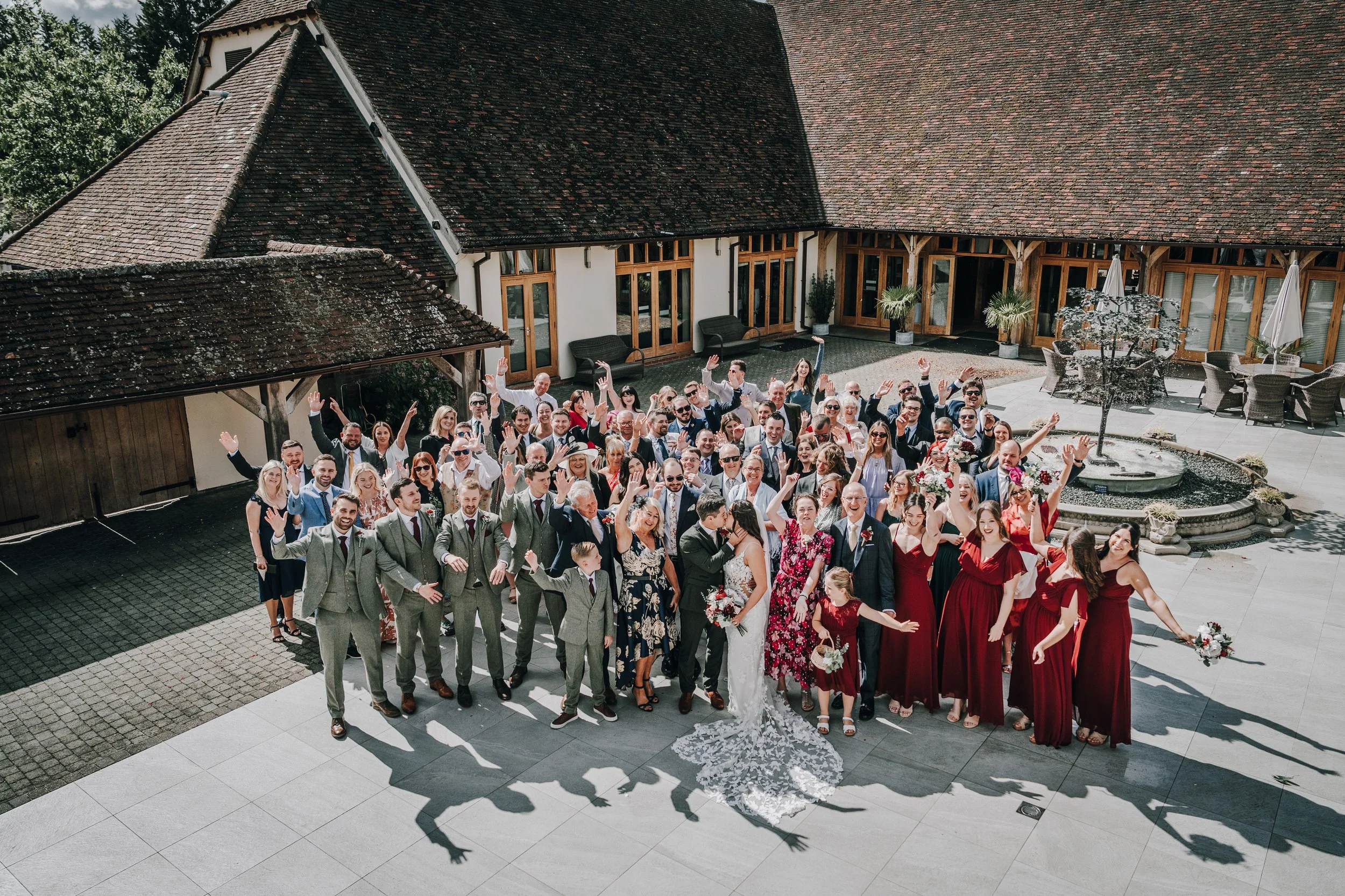 A large group of wedding guests gathered in a courtyard, celebrating a wedding, with a bride and groom in the center.