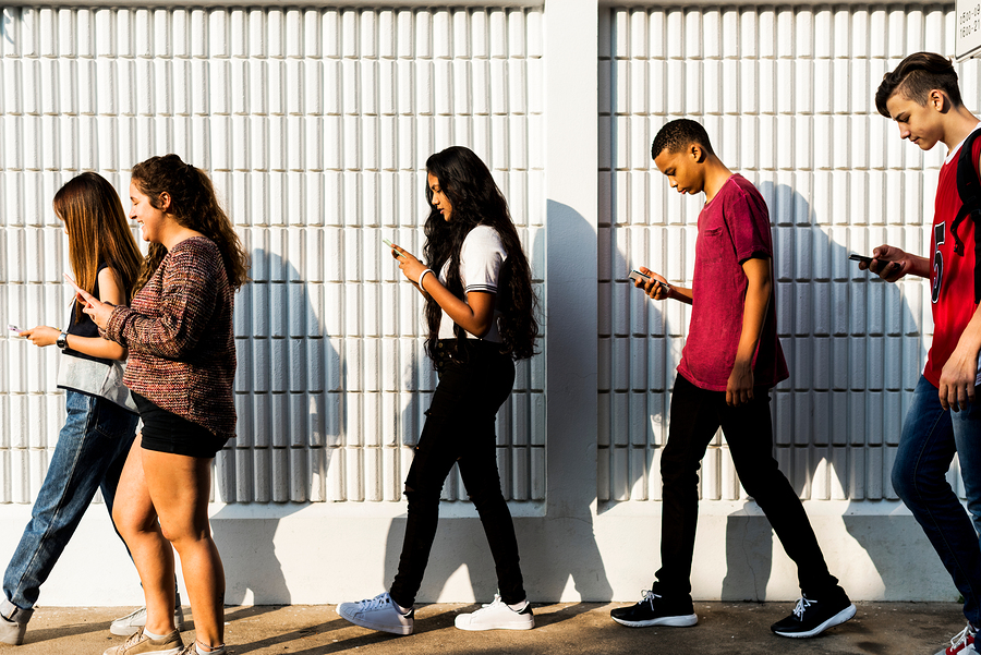 Adolescentes caminando y mirando sus redes sociales