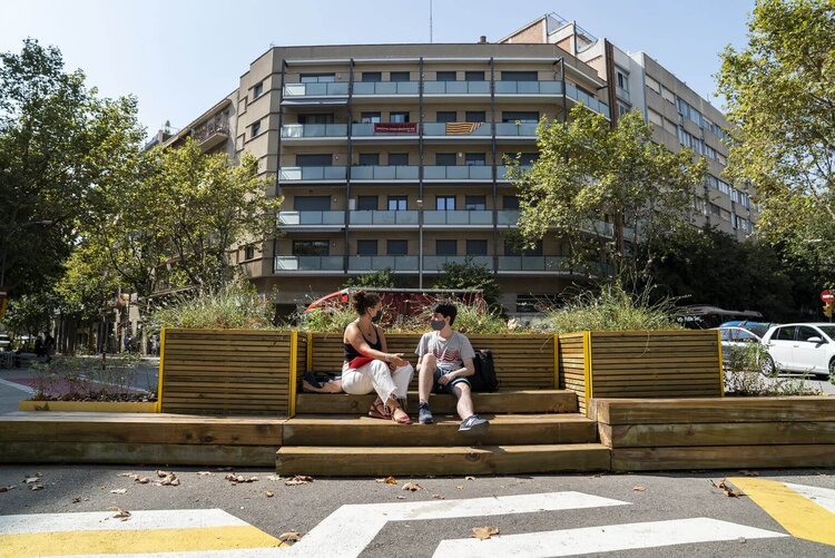 Dos jóvenes del Instituto Viladomat (Barcelona) conversan en las jardineras con bancos instaladas en la zona pacificada en torno al centro educativo. Foto por: Isaac Planella.