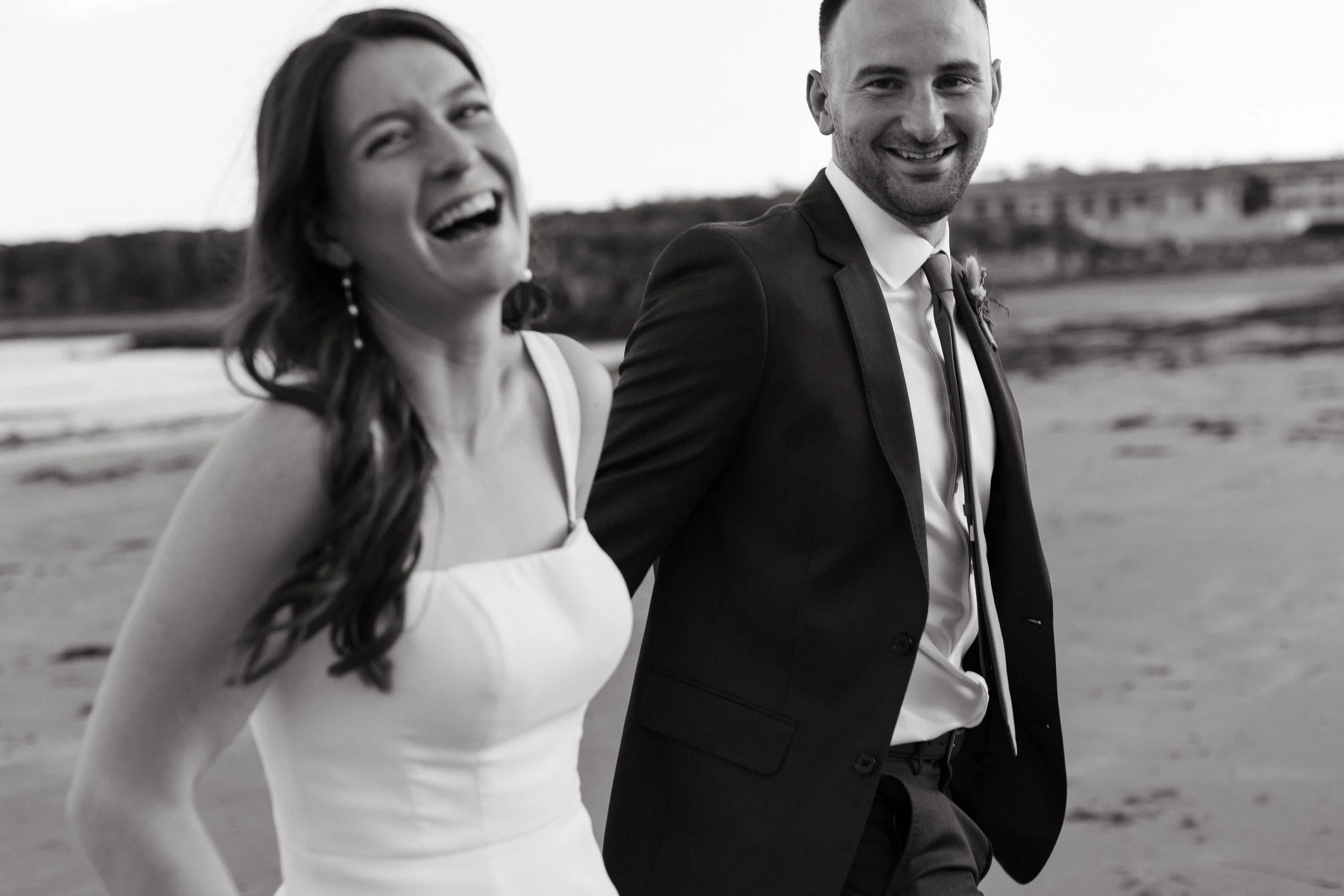 A couple laughing on the coast of Maine during their wedding day in York. Photography by Sienna Renee Photography.