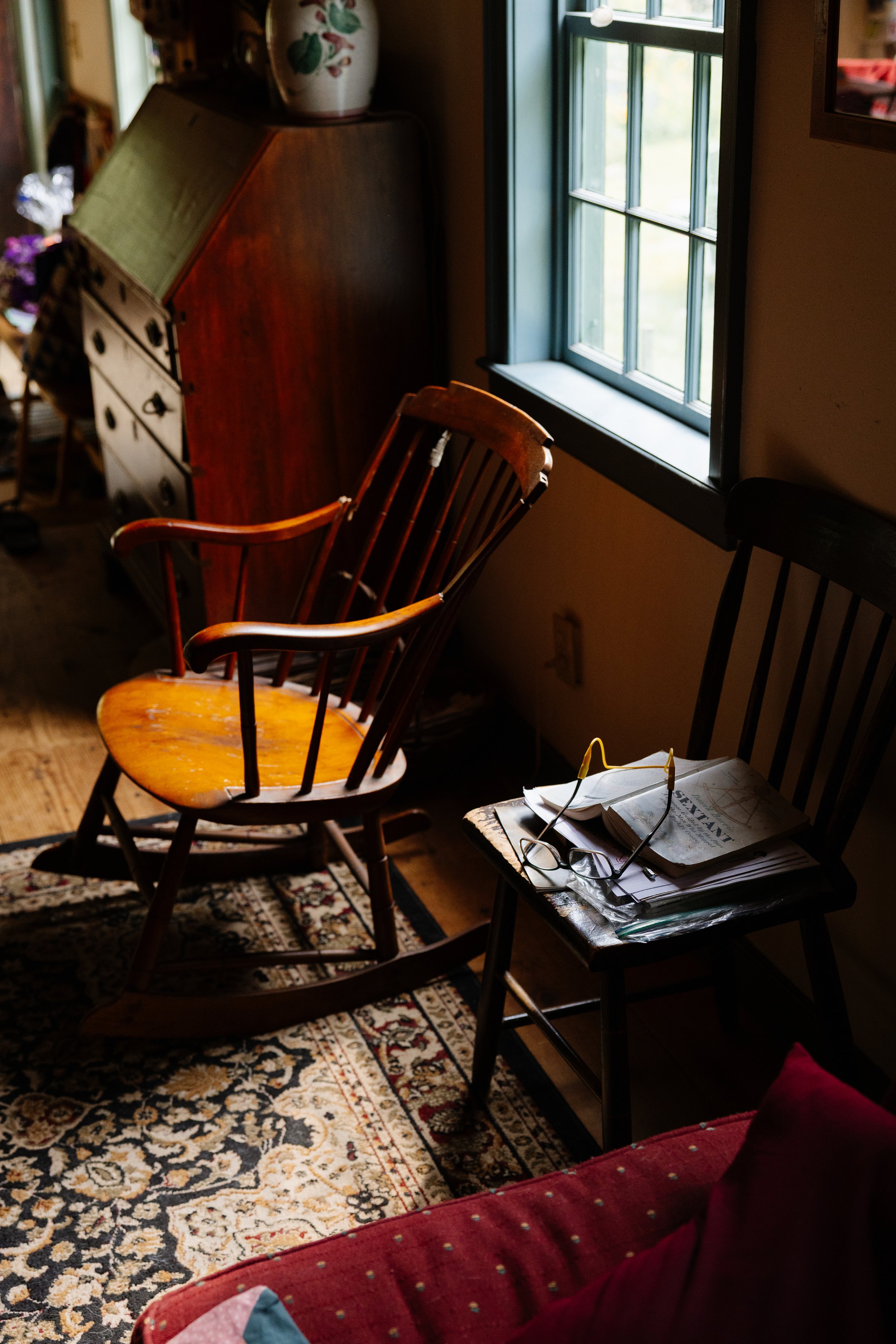Light on a chair, pair of glasses, and couch at a family home during a backyard wedding in Maine. Photography by Sienna Renee Photography.