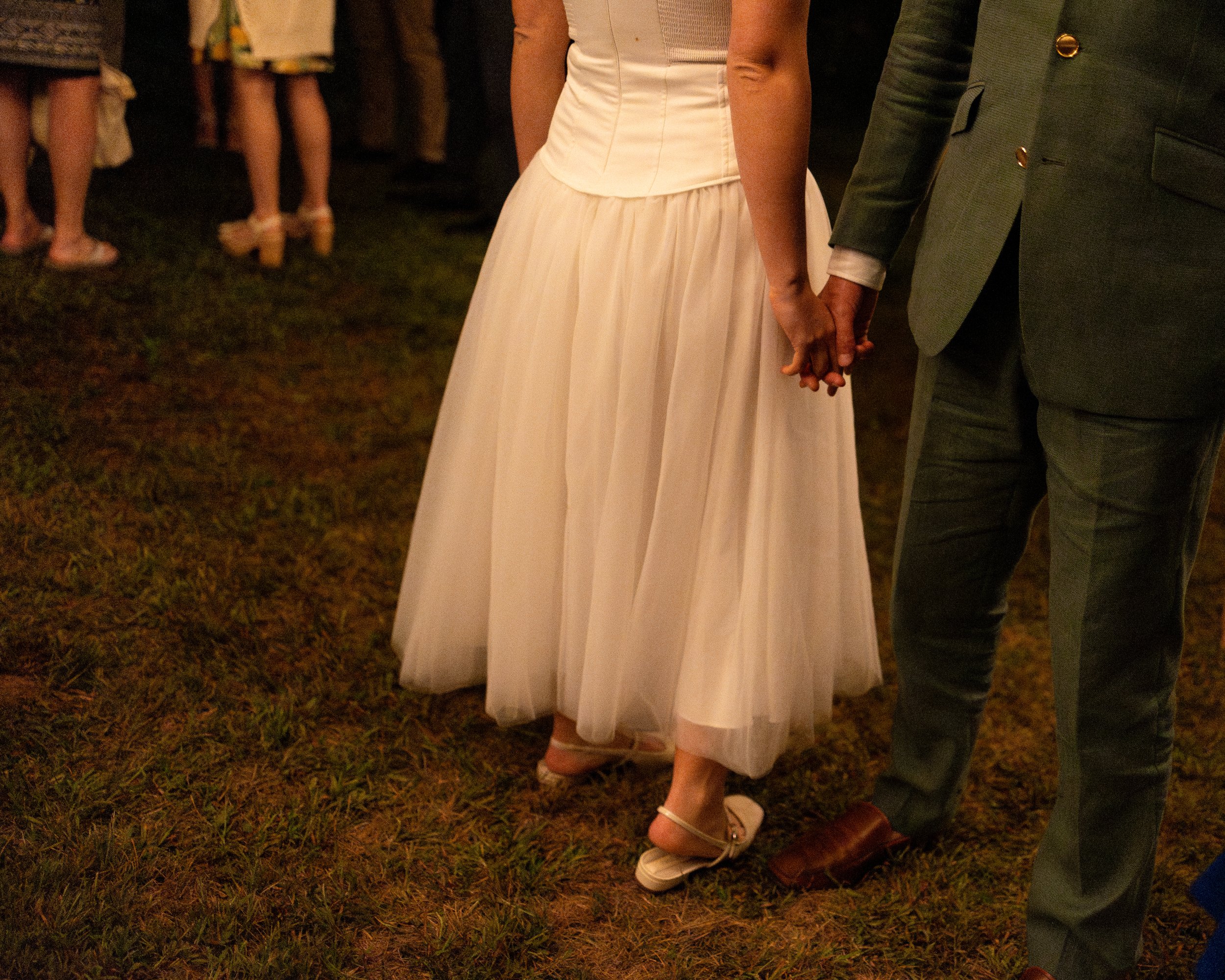 A couple holds hands during their small backyard wedding in North Berwick, Maine. Photography by Sienna Renee Photography.