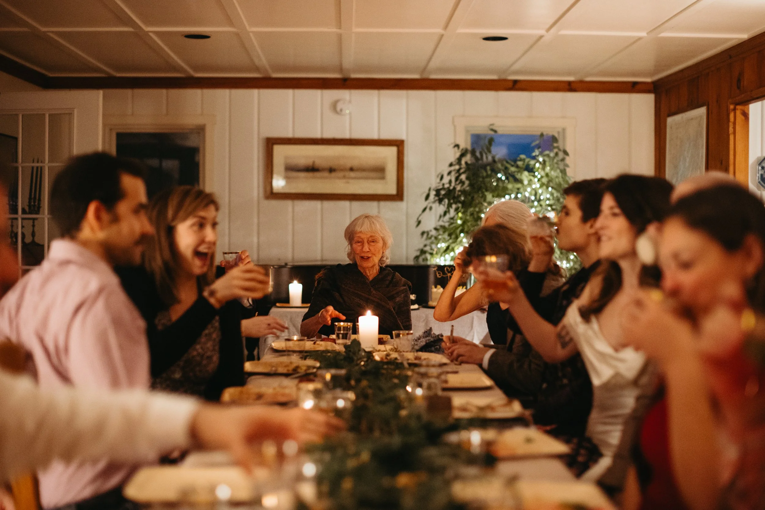 Guests sit down together for a family style dinner during an intimate wedding at a rental in Harpswell, Maine. Photography by Sienna Renee Photography.
