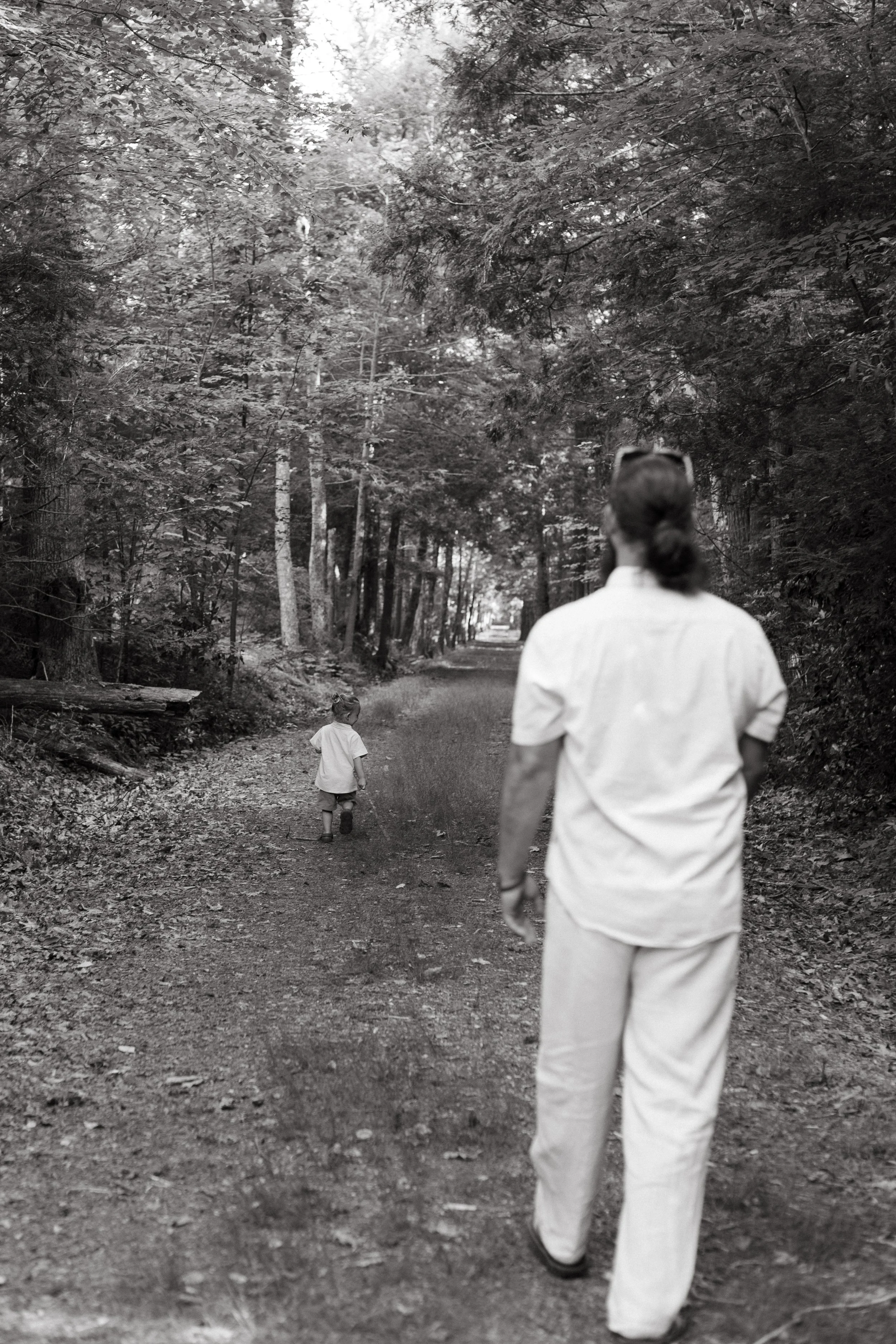 A dad and his son walk in the woods together during a family photography session. Photography by Sienna Renee Photography.