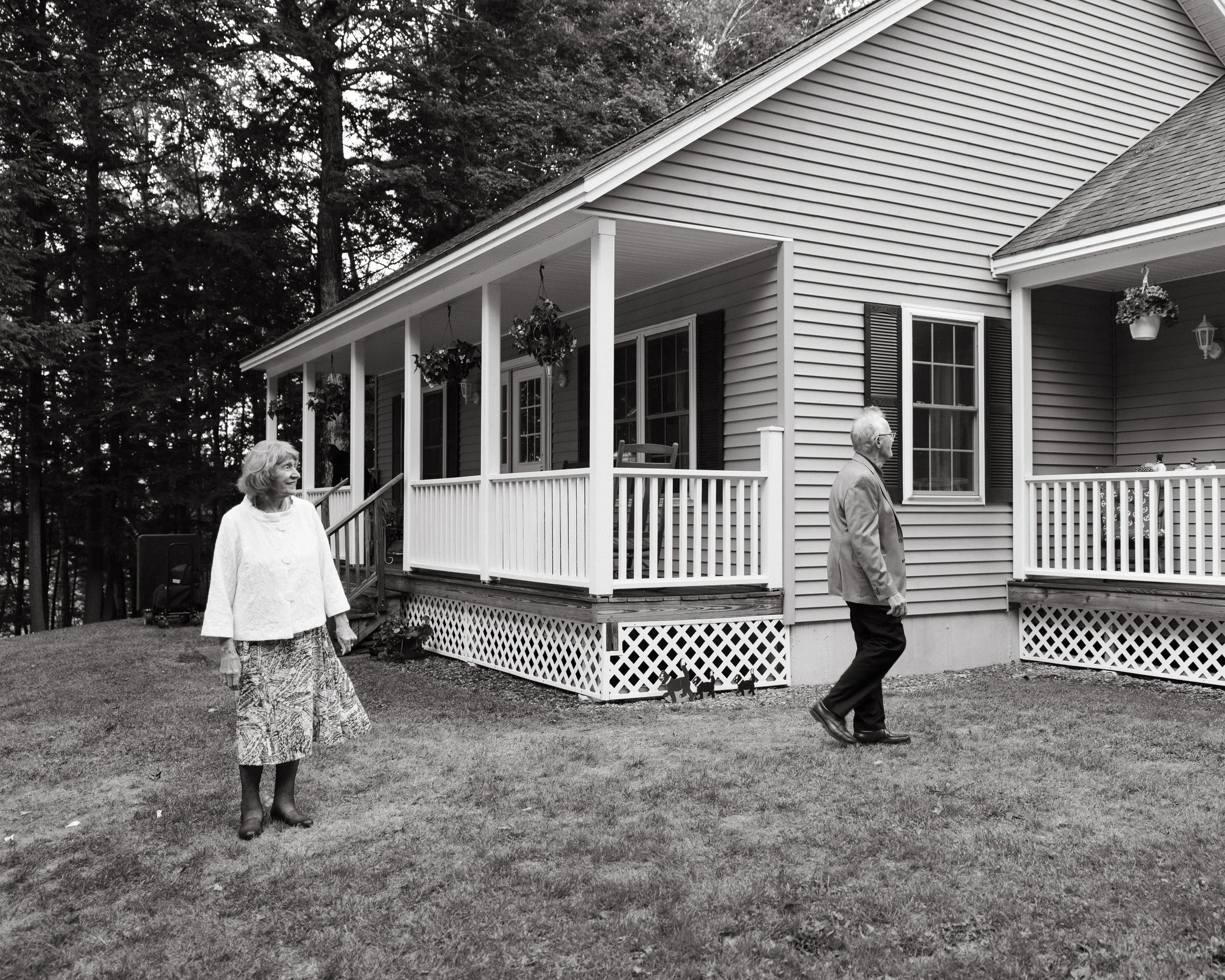 Grandparents of a couple walk in front of a home during a small backyard wedding in Maine. Photography by Sienna Renee Photography.
