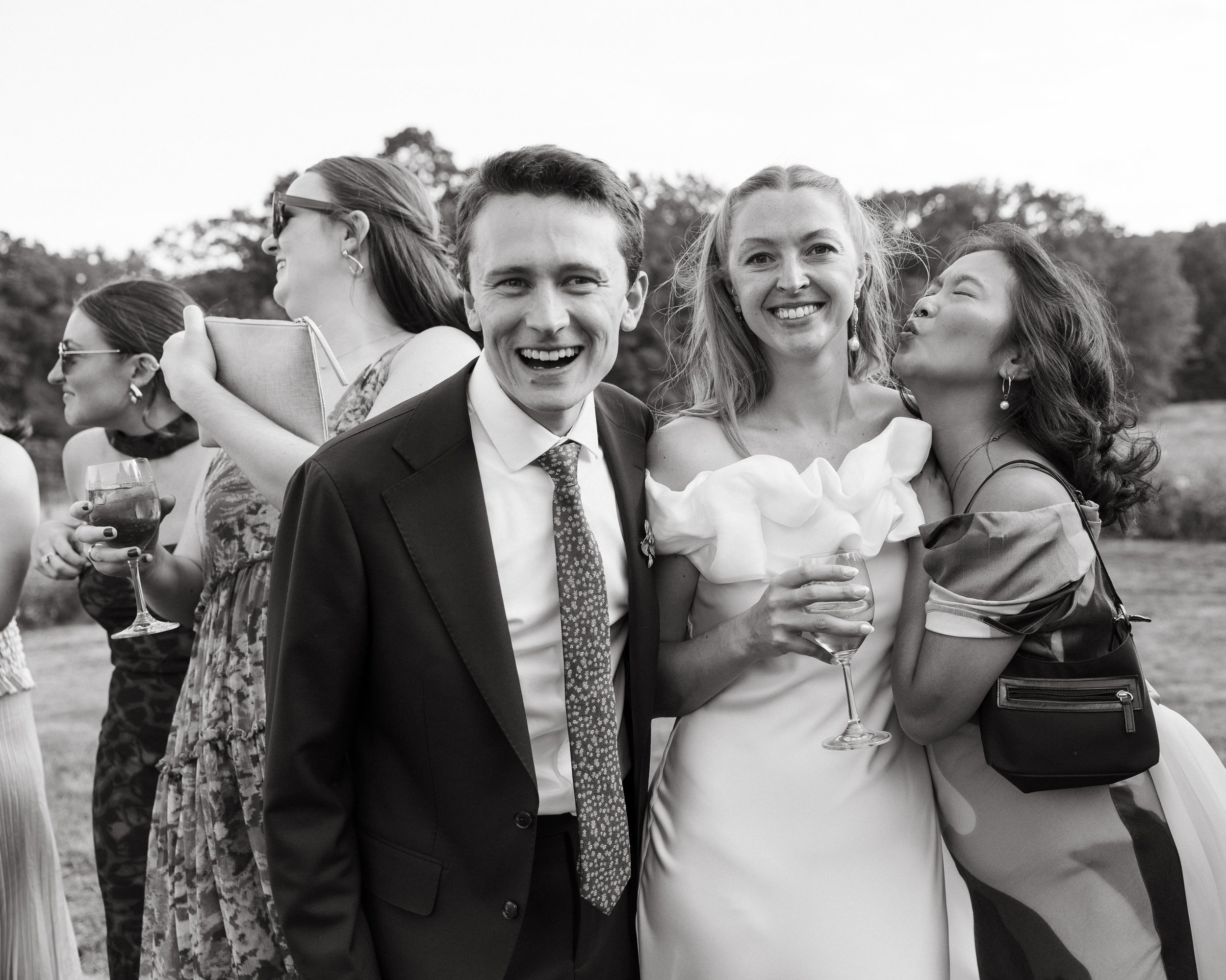 A couple and their guests together during a ceremony in the field at Scotland Fields in York, Maine. Photography by Sienna Renee Photography.