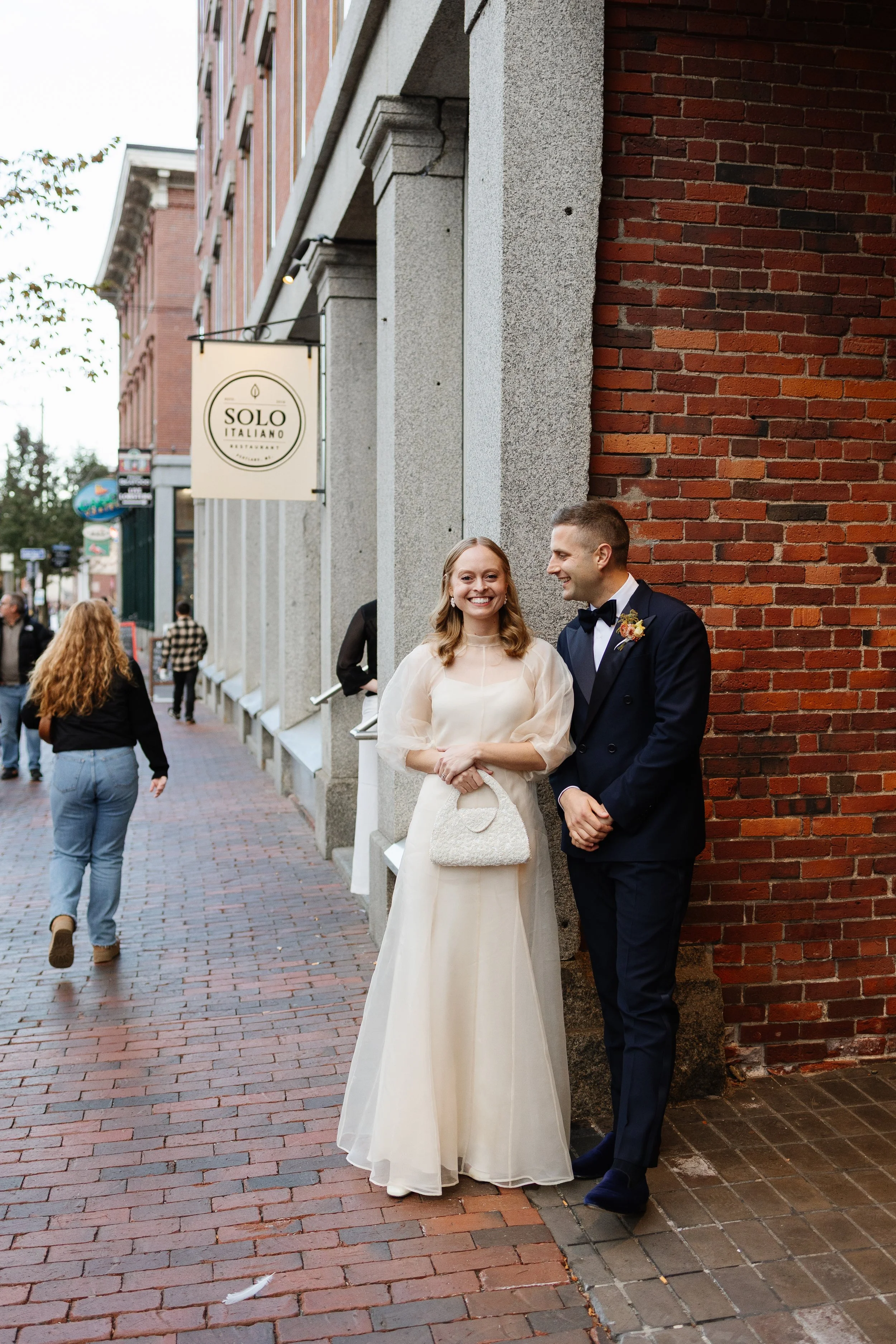 A couple smiles outside of Solo Italiano in Portland, Maine during their wedding reception. Photography by Sienna Renee Photography.
