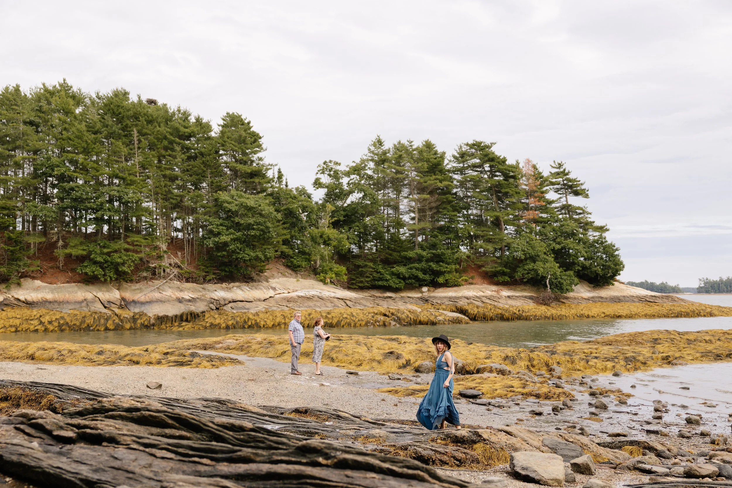A family stands by the water during a visit and photo session in Freeport, Maine. Photography by Sienna Renee Photography.