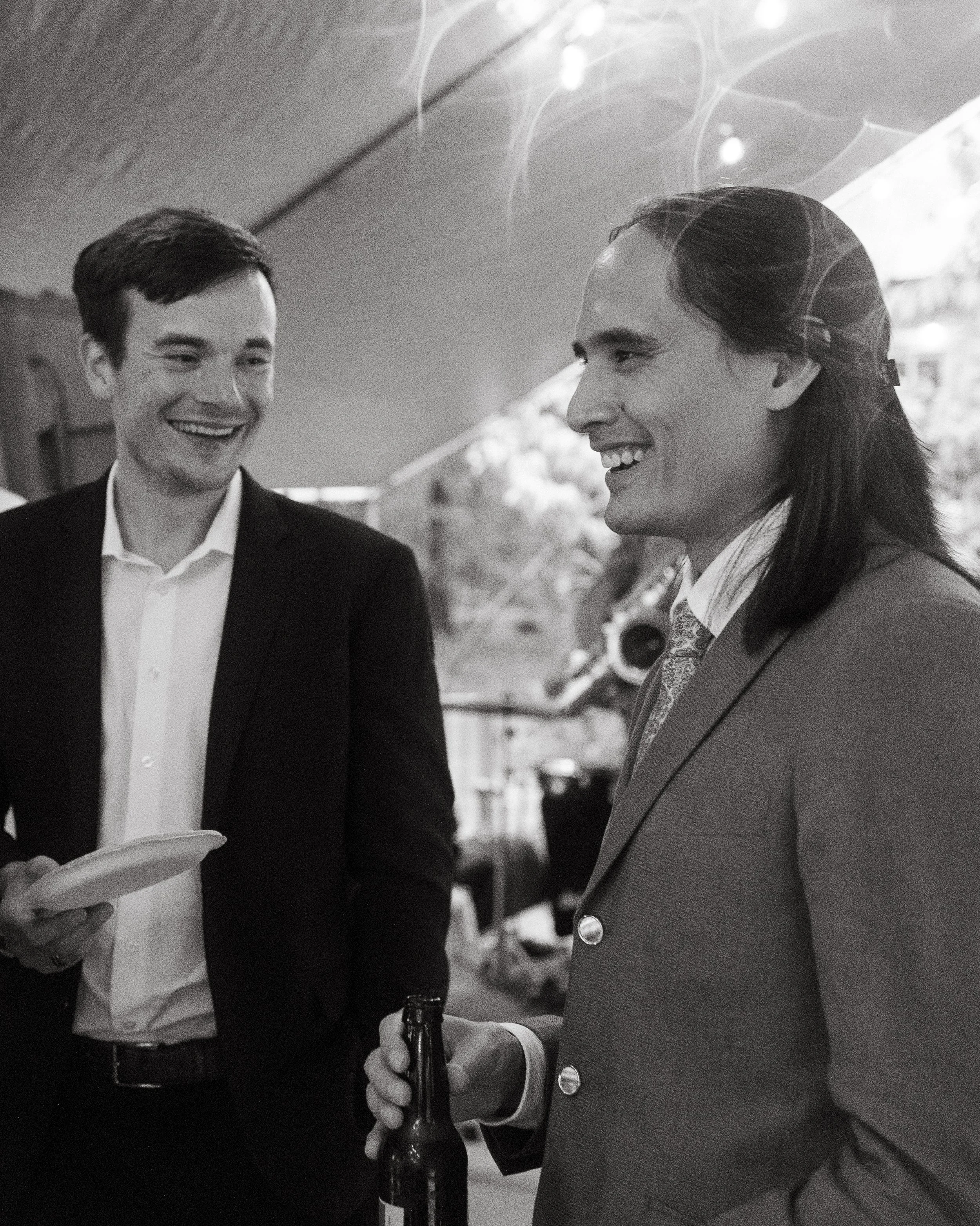 A groom laughs with friends and family during a rainy backyard wedding in Maine. Photography by Sienna Renee Photography.