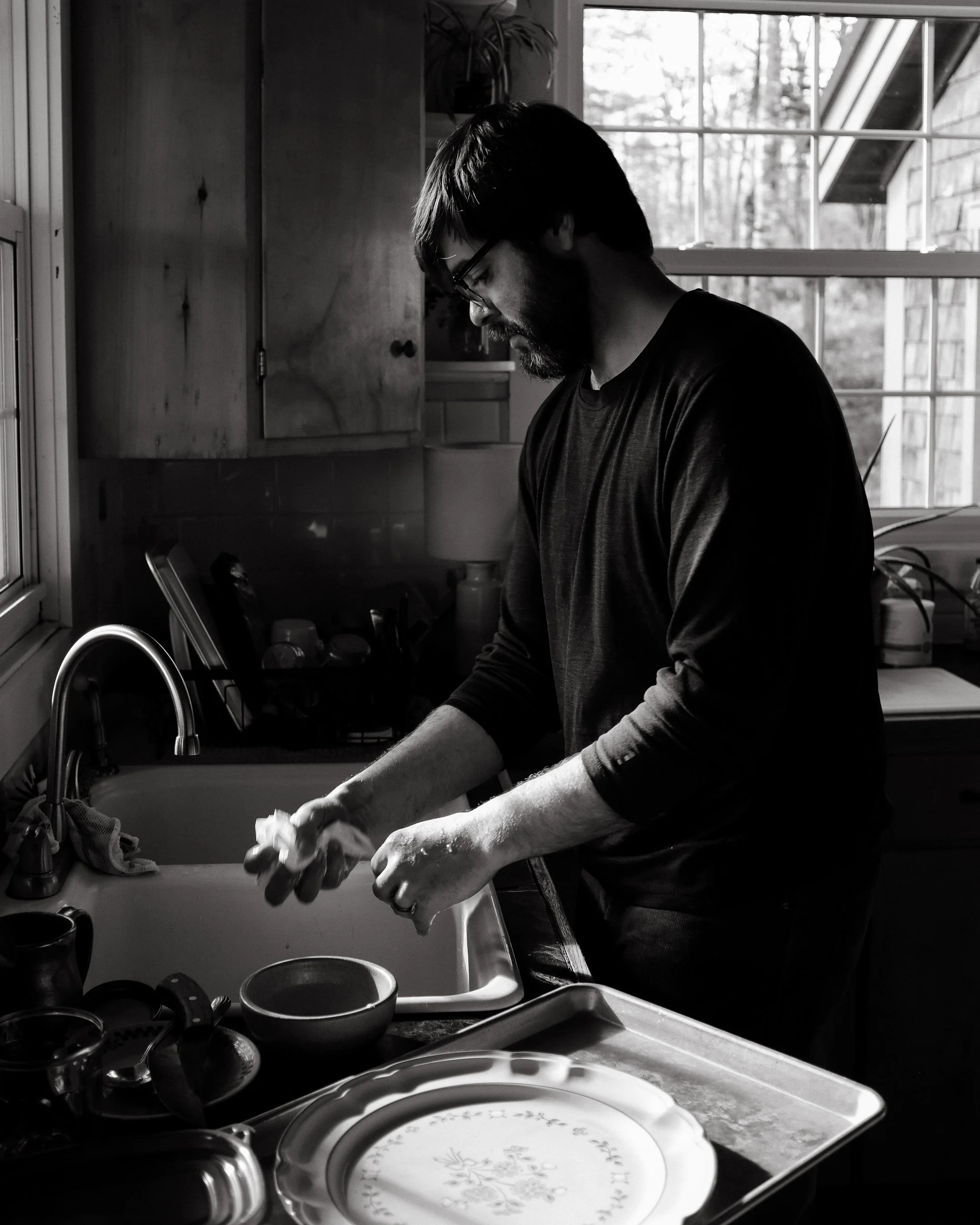 A man washes dishes at home in Maine. Photography by Sienna Renee Photography.