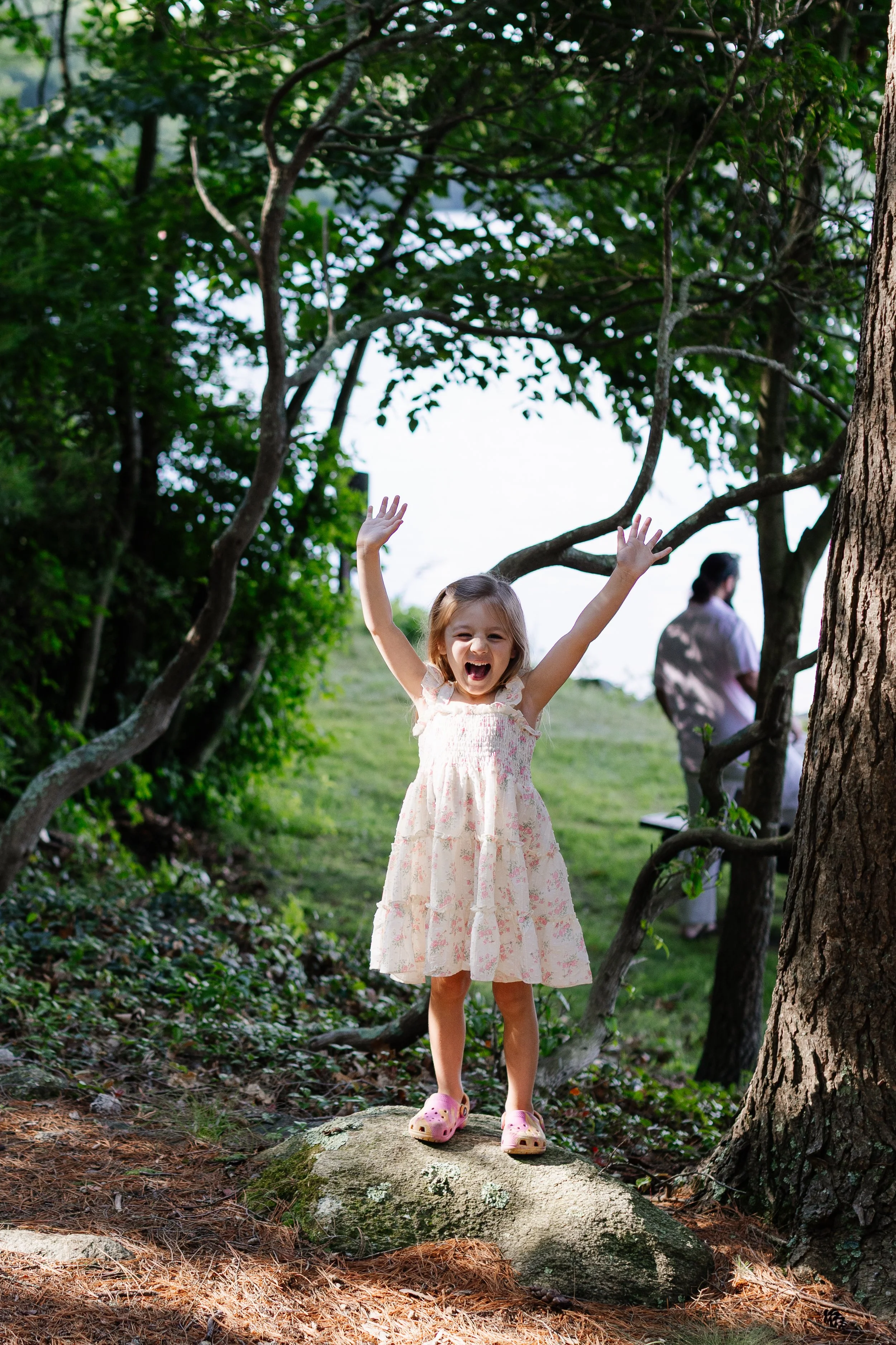 A young girl plays in the woods during a walk with her family. Photography by Sienna Renee Photography.