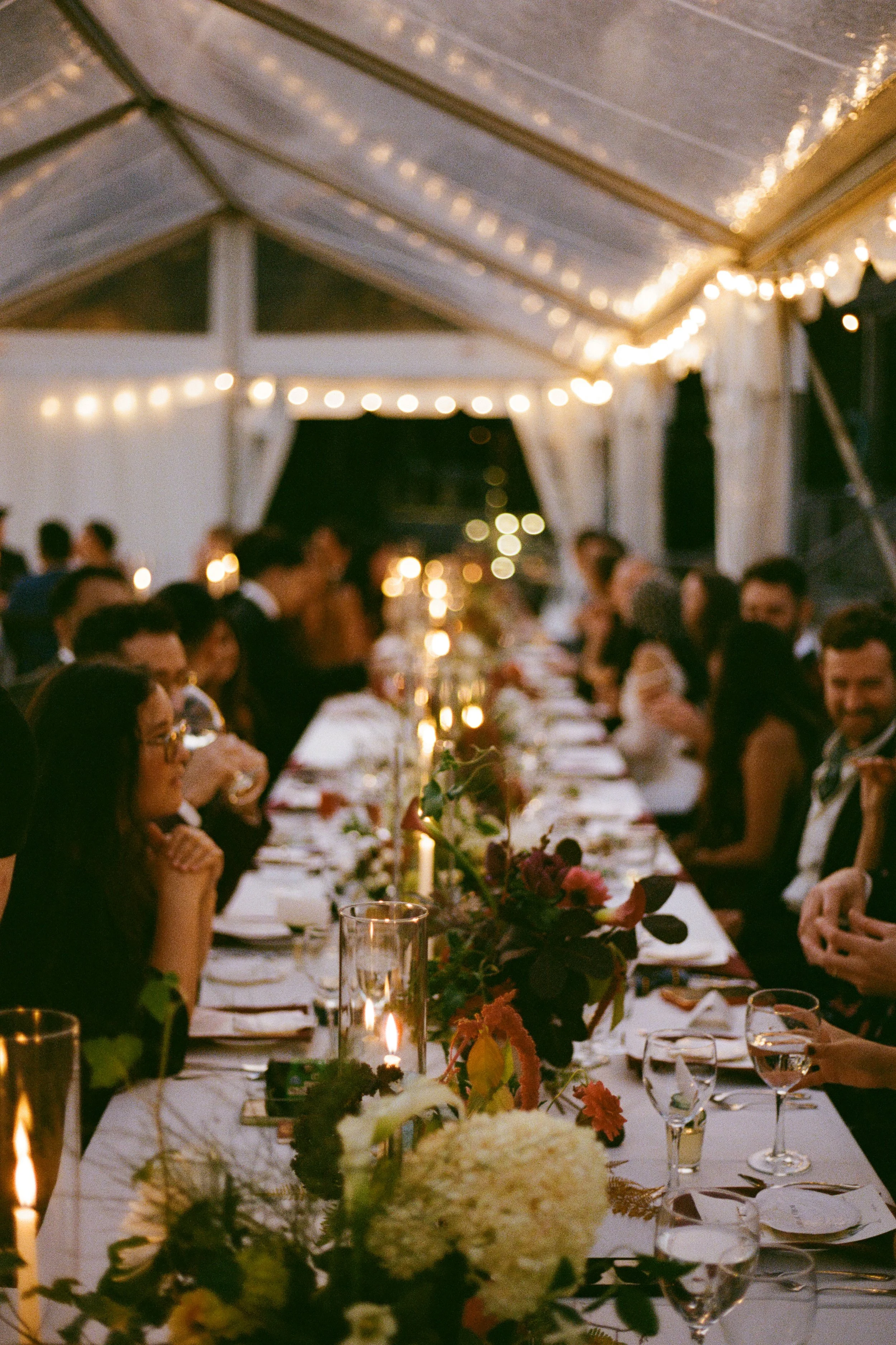 Table details on film of a family style dinner during a wedding celebration at Aragosta in Deer Isle, Maine. Photography by Sienna Renee Photography.