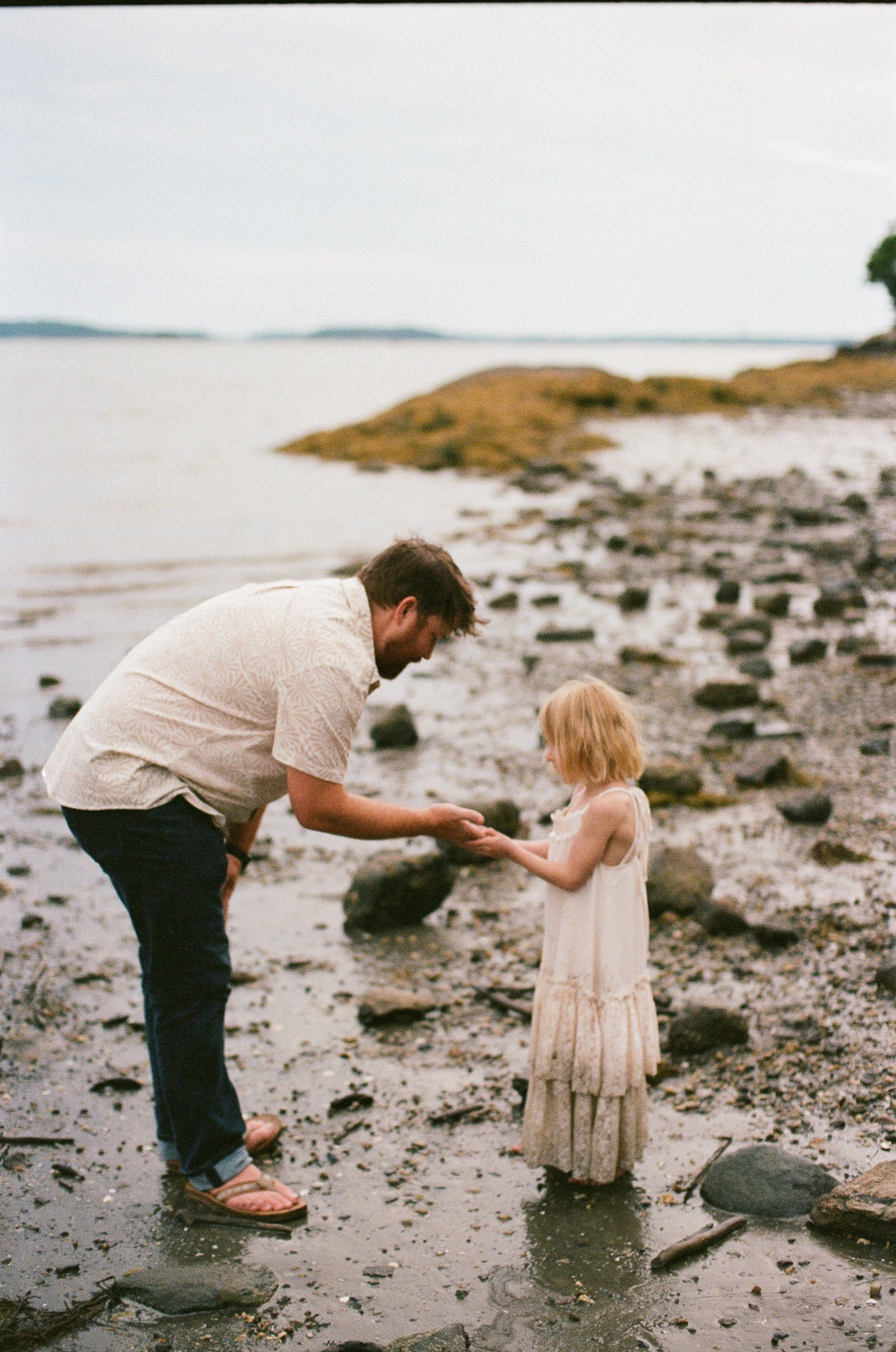 A dad shows his daughter a crab during a visit to the beach in Freeport, Maine. Film photography by Sienna Renee Photography.