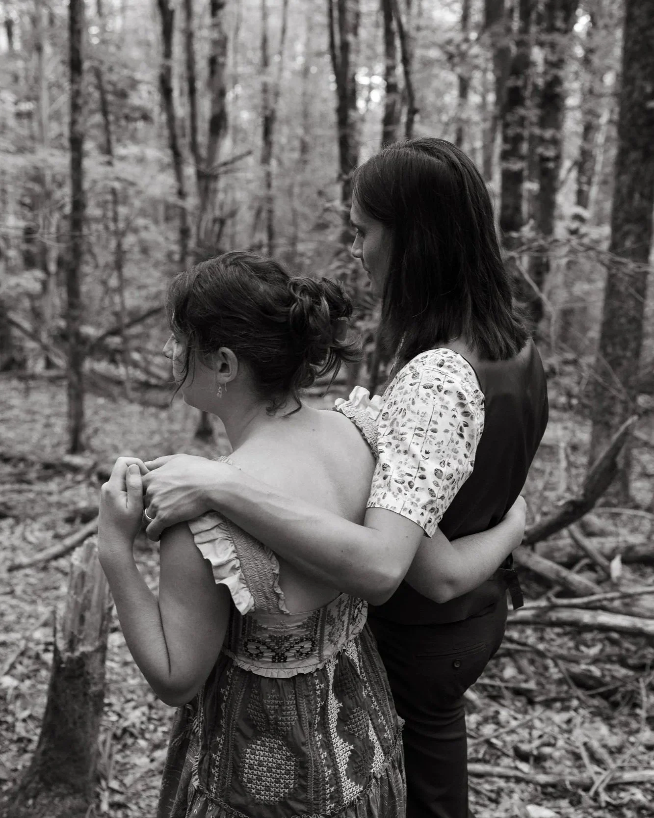 A couple has their arms around each other on a hike during their wedding celebration in North Brunswick, Maine. Photography by Sienna Renee Photography.